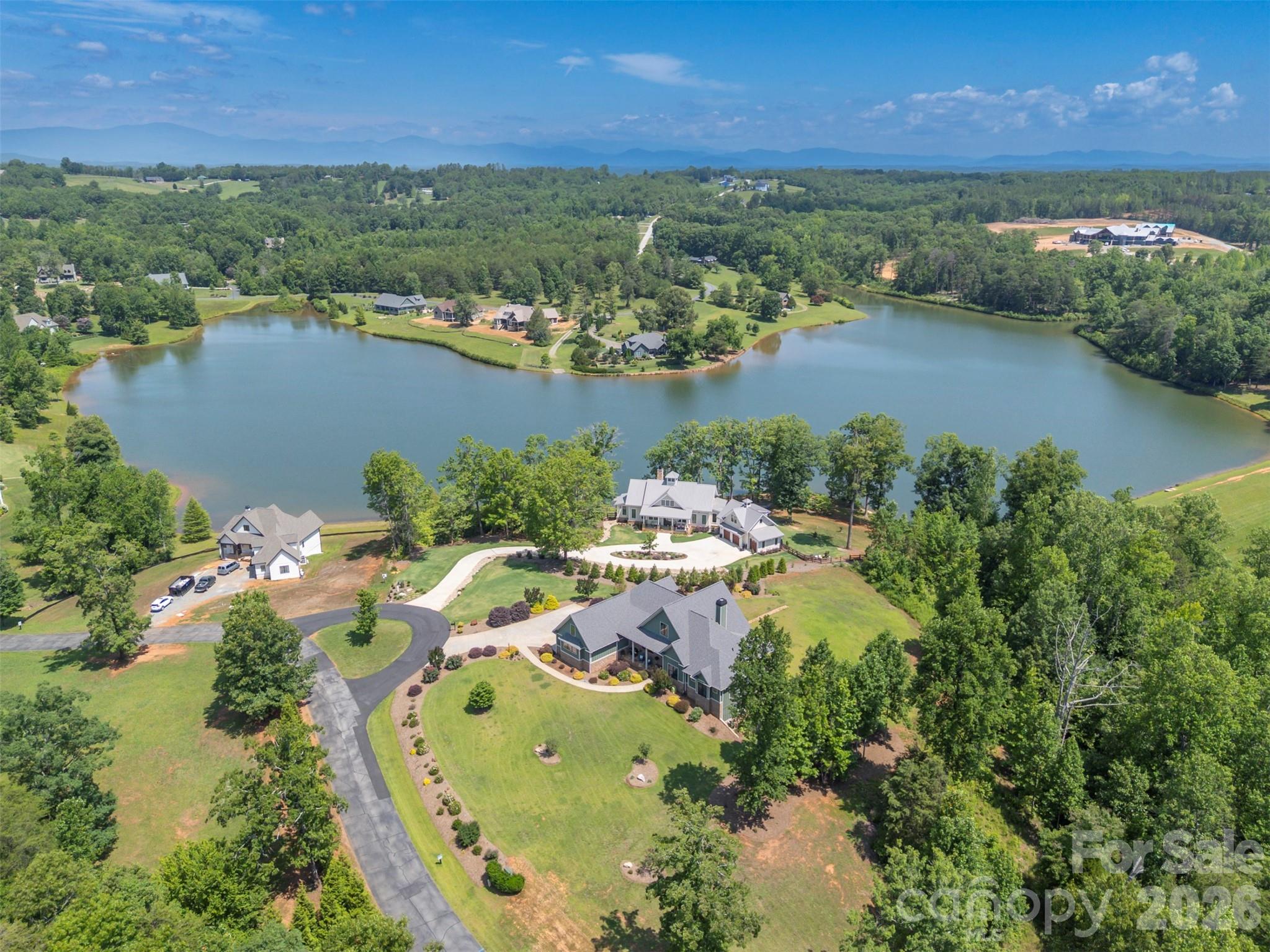 Welcome to your new home at "Derbyshire". Nestled in the rolling landscape of Columbus, North Carolina, Derbyshire is one of those places where life simply feels better.

The gated community Derbyshire was designed with a lifestyle in mind, with deep equestrian roots, including a large community barn, a well-maintained riding arena, a round pen, multiple paddocks and pastures, hay storage, a tack room, and direct access to both the CETA and FETA trail systems. An ideal area, whether you own a horse (or two!) or just love the beauty of tree-lined streets and classically fenced pastures.

At the center of Derbyshire sits Lake Sandy Plains, a 33-acre spring-fed lake. The lake views from your new home are breathtaking. Take a leisurely walk around the lake, fish, kayak, paddle board, canoe, and swim! Enjoy about 8 miles of walking trails around the community, or beautiful misty mornings and quiet sunsets. It won't take long to spot the "local" turtles basking on a log, the daily flights of a family of geese, and a lovely Blue Heron keeping a watchful eye on his kingdom. 

Your new home is set on an elevated 1.27-acre lot with the option to purchase the adjoining treed lot for additional space and privacy. This custom-built home was completed in 2020 by Mapleton Lane Custom Homes. This spacious home spans 5,314 square feet across three beautifully finished levels, offering space for hobbies, extended families, exercise, entertainment, and comfort. 

The main level, with its tall ceilings, offers 2,679 square feet of exceptional living space, centered on an open family room/dining/kitchen floor plan. The kitchen has a breakfast bar, a walk-in pantry, built-in features, and premium appliances. A dedicated home office provides a quiet retreat for work or reading, while the main-level laundry and mudroom add everyday practicality.

The primary bedroom suite on the main level is a genuine sanctuary — nearly 284 square feet with two walk-in closets and a luxurious en-suite bath featuring a large shower and free-standing tub. At the other end of the home, on the main level, are two additional bedrooms that share a well-appointed full bath, making single-floor living entirely achievable for those who want it.

Above the main level is a private 908-square-foot bedroom suite with its own full bath, ideal for family members returning home, long-term guests, a live-in caregiver, or even a creative studio retreat. It functions as a self-contained escape with its own sense of privacy and quiet. 

Downstairs, the walkout lower level adds 1,726 square feet of finished space, including a full bath, wet bar, ample storage, and flex space for an additional private living area, hobbies, a home gym, or whatever your imagination can conjure. And let's not forget the 390+ square feet of space, ideal for a workshop, with exterior access via an overhead garage door. 

Modern infrastructure completes the picture. Derbyshire is served by fiber optic internet, natural gas, municipal water, underground utilities, and underground power lines — meaning you enjoy the beauty and peace of mountain-adjacent country living without sacrificing a single convenience. Each floor has its own zoned heating and cooling, a whole-home approach to energy efficiency. 

This is not just a home. It's a way of living — unhurried, secure, beautiful, and only minutes from Landrum, SC, Tryon, and Columbus, NC. Derbyshire is only 20 minutes from Greenville and Spartanburg, SC, and 40 minutes from Asheville, NC. This peaceful jewel in the heart of horse country won't be available long...