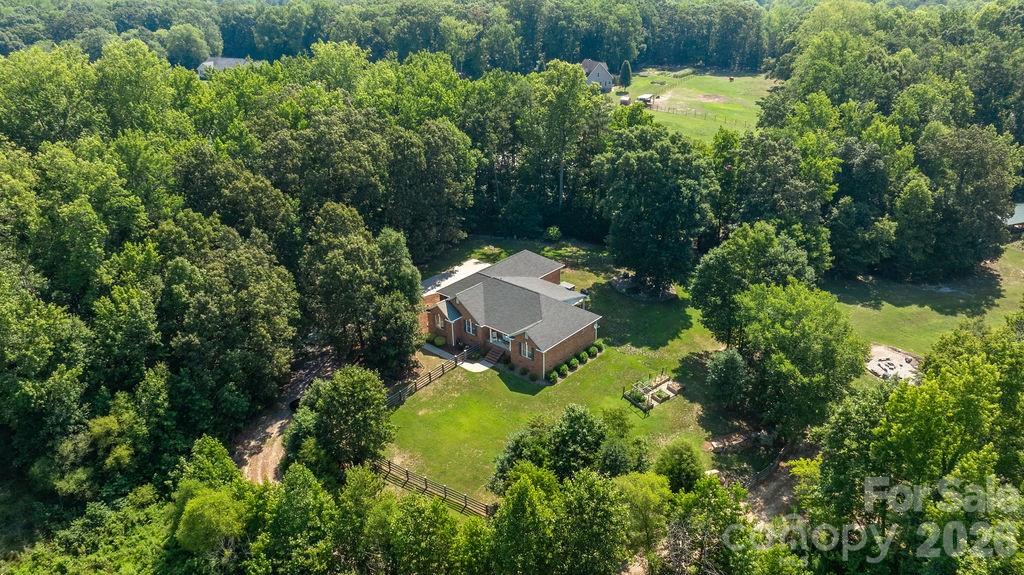 Tucked away at the end of a long private drive, this custom brick ranch offers more than a home, it offers a lifestyle. Set on over 20 beautiful acres just 15 minutes from downtown Salisbury, this private country estate is where peaceful mornings begin on the back porch overlooking rolling pasture and wooded landscape, afternoons are spent exploring the private trails, and evenings end gathered around the fire pit beneath the Carolina sky.
Designed for both comfort and functionality, this thoughtfully crafted one-story home features three bedrooms, two full bathrooms, and a flexible floor plan that includes a dedicated office or optional third bedroom. Elegant
tray ceilings accent the living room, formal dining room, and spacious primary suite, while rich oak hardwood flooring flows throughout the main living areas. At the heart of the home, the inviting living room centers around a cozy fireplace, creating a warm gathering space year-round. The kitchen is beautifully appointed with granite countertops, Bosch stainless steel appliances, abundant cabinetry, a breakfast bar, and an additional dining area for casual meals, while the formal dining room provides the perfect setting for holidays and entertaining. A dedicated laundry room adds everyday convenience. The spacious primary suite serves as a private retreat, complete with two walk-in closets and an en-suite bathroom featuring two independent vanities, whirlpool soaking tub, separate walk-in shower, and generous storage. Step outside and discover what truly makes this property extraordinary. Approximately 20.35 acres, mostly wooded, provide unmatched privacy while still offering open areas ideal for recreation, gardening, or hobby farming. Wander the established trails, relax beside the spring-fed creek, enjoy evenings around the fire pit, or simply unwind on the expansive back porch while watching deer, birds, and other native wildlife pass through the property. The outdoor shower is the perfect finishing touch after a day working outdoors, hiking the trails, or giving your four-legged companion a bath.
Practical features are just as impressive. The attached three-car garage doubles as an exceptional workshop, while the Amish-built pole barn with its reinforced concrete pad provides outstanding storage for tractors, equipment,  recreational vehicles, or future customization. The property is partially fenced and offers endless possibilities for those dreaming of a hobby farm, homestead, or private countryside retreat.
Modern conveniences blend seamlessly with rural living, including a private well, septic system, and PoE security camera system with facial recognition technology for added peace of mind. With no HOA restrictions, you'll enjoy
the freedom to truly make this property your own. Properties offering this level of privacy, acreage, quality construction, and convenience rarely become available. Whether you're seeking a forever home, a weekend escape, or the opportunity to create your own private estate, 625 Jackson Road is a rare opportunity to experience the very best of country living without sacrificing easy access to shopping, dining, and everyday conveniences.