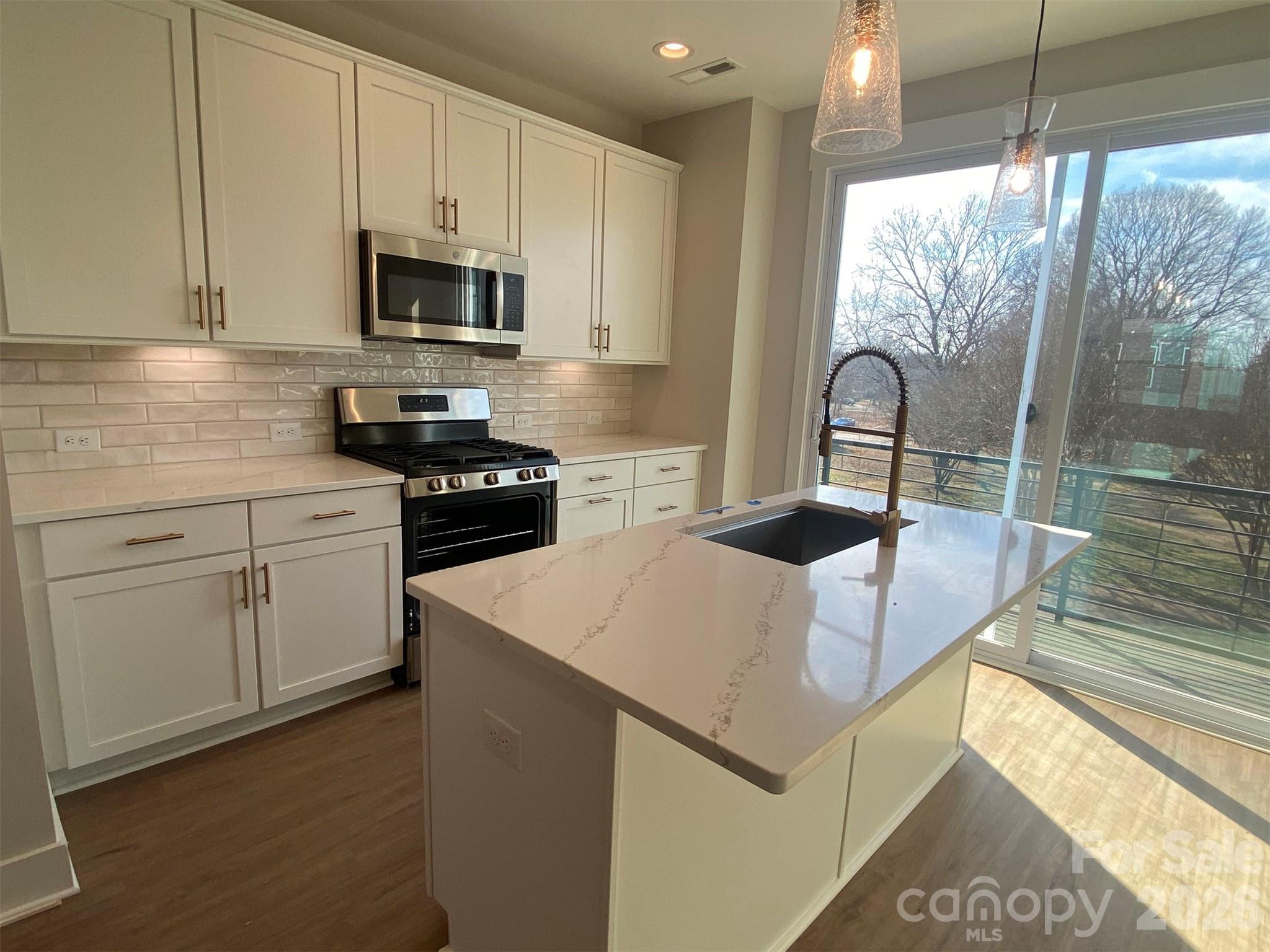 Versatile 4-story townhome, with a 4th floor bonus bedroom & rooftop terrace, plus 1st floor Flex rm w/ powder! The open layout of the second floor makes entertaining a snap, or meet friends at Camp North End just across the street. Kitchen features 42" white painted cabs w/ brushed gold hardware, quartz counters, backsplash, under-cabinet lights, trash pullout, pantry cabinet, GE SS app w/ gas range, & large undermount SS sink. Laundry is on the 3rd floor w/ the bedrooms. Premier Bath has light grey painted cabs, quartz counters, tiled floors & tiled shower w/ semi-frameless glass. Guest hall bath has white painted cabs, quartz counter, tiled floor. LVP floors throughout the 1st & 2nd floors, plus 3rd floor hall, w/ tile in full baths, 1st floor powder, & laundry. Oak treads on all stairs. 4 fans included, 9' ceilings throughout; 1-car garage & driveway plus on-street parking is available. Enjoy close proximity to Uptown Charlotte.