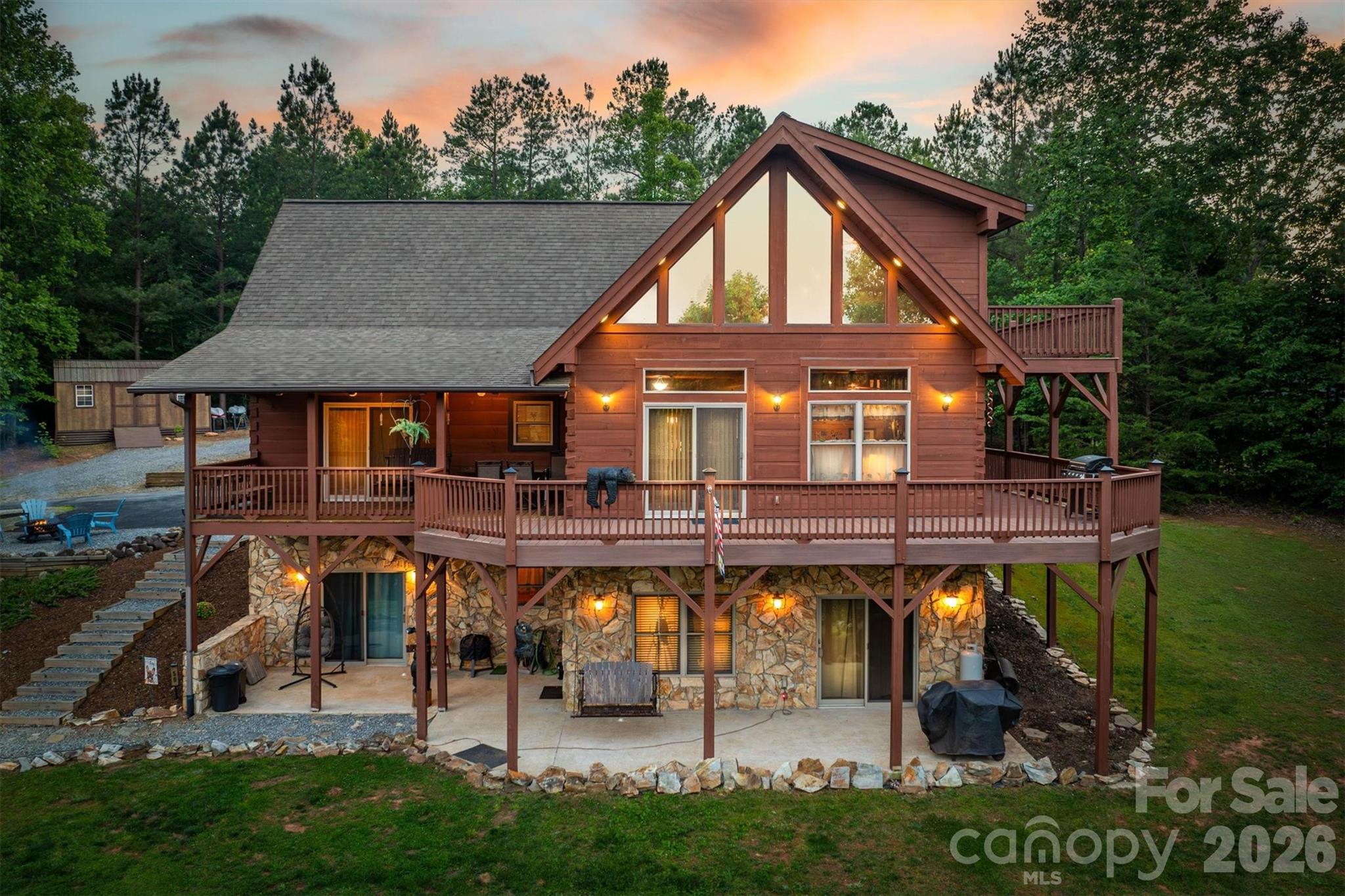 NEW PRICE IMPROVEMENT!! EXCEPTIONAL VALUE!! Spectacular handcrafted log home, complete with a private in-law suite tucked seamlessly into the lower level.  Nestled on 1.6 acres in Grandview Peaks, a gated mountain community located in the heart of the Blue Ridge Mountains! The fully finished basement offers exceptional flexibility - perfect as a private in-law suite for multigenerational living, a comfortable space for extended family or guests, or an income-producing rental opportunity.  It offers easy access & privacy with a separate dedicated driveway and entrance as well as a full kitchen, family room, en-suite bedroom and 2nd laundry room. The primary floor has all you need for main level living.  The entryway opens to a spacious dining area, leading to the large kitchen w/ an eat-in island, gorgeous wood cabinets and a convenient walk-in pantry. The laundry room shares space with a half bathroom. The primary en-suite is open with high ceilings, a walk-in closet and a small loft tucked away for added storage space.  Just steps away, the bedroom opens to the covered back porch where you can sip your morning coffee. Upstairs you'll find an open loft that's the perfect space for a home office/workout or hobby room. The second en-suite bedroom is also in the loft with it's own open deck to enjoy the surrounding nature and mountain views. Loft deck was just upgraded with composite material for easy maintenance. Outdoor living here is every bit as enticing as inside with covered wrap-around porches & a level backyard for gardening, a playground, or relaxing around the campfire. The landscape waterfall below the yard is not part of the property - it is community owned and maintained.  Leading to the front entrance is a huge attached carport, tall enough to store an RV or boat & a detached 2-car garage & separate storage shed. No dangerous steep roads here! This home sets the tone for the whole community, as it's the first thing you see when you come through the gates. The location also cuts down on your drive time to the charming towns of Marion & Morganton. Looking for a taste of city life?  Asheville is just 45 minutes away. Residents enjoy swimming & fishing at the private community lake & beach. There's 5 miles of nature trails for hiking and weekly community gatherings at the lakeside pavilion. From the moment you arrive, this well cared for home invites you to live the dream - where rustic charm meets modern comfort. Schedule your tour today!