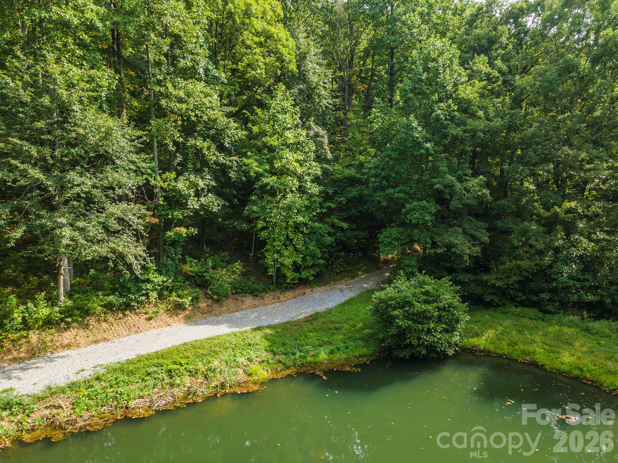 Have you seen this lot yet? If not, you’re missing out. Septic and well permits in place. Ready to start your home building project. Tucked within the quiet forest of Gateway Mountain, this 1.84-acre parcel with a spectacular pond and Mountain Views is a story book setting. Sheltered by tall hardwoods and draped in mountain laurel, rhododendron, and fern, this homesite offers a rare combination of privacy, easy build potential, and stunning pond frontage. The gentle slope provides flexibility for building, whether your dream is a cozy timber cabin or a modern mountain escape with glass walls opening to the view. There’s space to breathe, garden, and grow — all surrounded by the natural rhythms of the Western North Carolina mountains. Located in the gated community of Gateway Mountain, residents enjoy miles of walking trails, private lakes, creeks, and picnic areas, all lovingly maintained to preserve the land’s wild beauty. This is not a crowded subdivision — it’s a true nature sanctuary, where each property is spacious, wooded, and alive with mountain character. And though you’ll feel far away from everything, the essentials are close at hand. The vibrant small town of Old Fort is just down the mountain, and Asheville, Black Mountain, and Marion are an easy drive away — offering art, music, local markets, and restaurants that celebrate mountain living. Here, you can disappear into the woods without disconnecting from the world entirely. HOA fees cover road maintenance, the security gate, and the preservation of this extraordinary mountain environment. Don’t wait long, someone is going to fall in love with this place — it might as well be you.