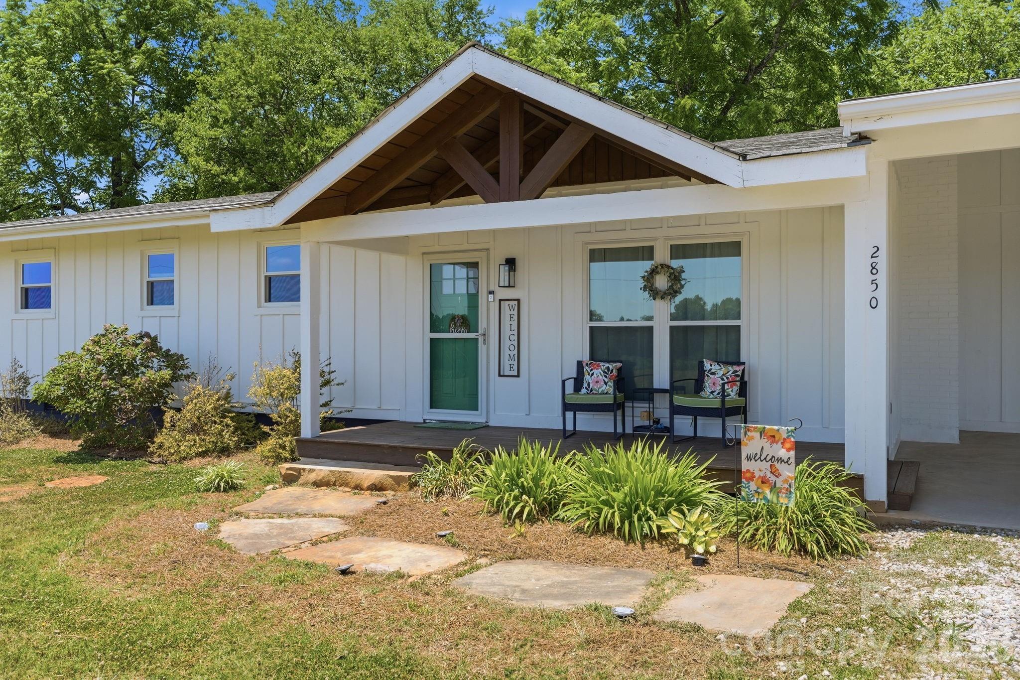 Tucked away in the peaceful countryside of Catawba, this one-of-a-kind timber-frame home blends rustic character with thoughtful modern updates on a beautiful, private setting. Originally stick-built in 1969 and relocated to its current site in 2012, the home showcases stunning architectural details throughout, including gorgeous vaulted ceilings with white-painted wood panels, dark-stained exposed beams, and a dramatic, stacked-stone, decorative, floor-to-ceiling fireplace that serves as the showpiece of the great room. The open layout flows from the great room into the dining area and spacious kitchen featuring granite countertops, black-painted real wood cabinetry, tile backsplash with decorative accents, island with breakfast bar, and Samsung dark stainless appliances. Each of the 3 bedrooms enjoys its own ensuite bath, creating a comfortable and private retreat for family or guests. The primary suite overlooks the peaceful wooded back yard and includes a walk-in closet plus a beautifully updated bath with tiled shower and granite vanity. A versatile bonus/flex space offers laminate wood floors, a full bath, laundry area with sink, private exterior access, and a new heat pump installed in February 2025. Outdoor living shines with a vaulted and beamed front porch, back deck, fire pit area, and attractive landscaping additions. Additional highlights include hardwood floors installed during the 2012 relocation, updated plumbing, upgraded 200-amp electrical service, new windows and doors in 2021, board and batten siding, new crawl space vapor barrier in 2025, walk-up attic storage, and an oversized 2-car carport with vaulted exposed beam ceiling. The powered and insulated storage building with quartz workbench adds even more versatility for hobbies, storage, or workshop use. This truly special property offers the warmth and craftsmanship of a mountain-style retreat while still being convenient to nearby towns and amenities.