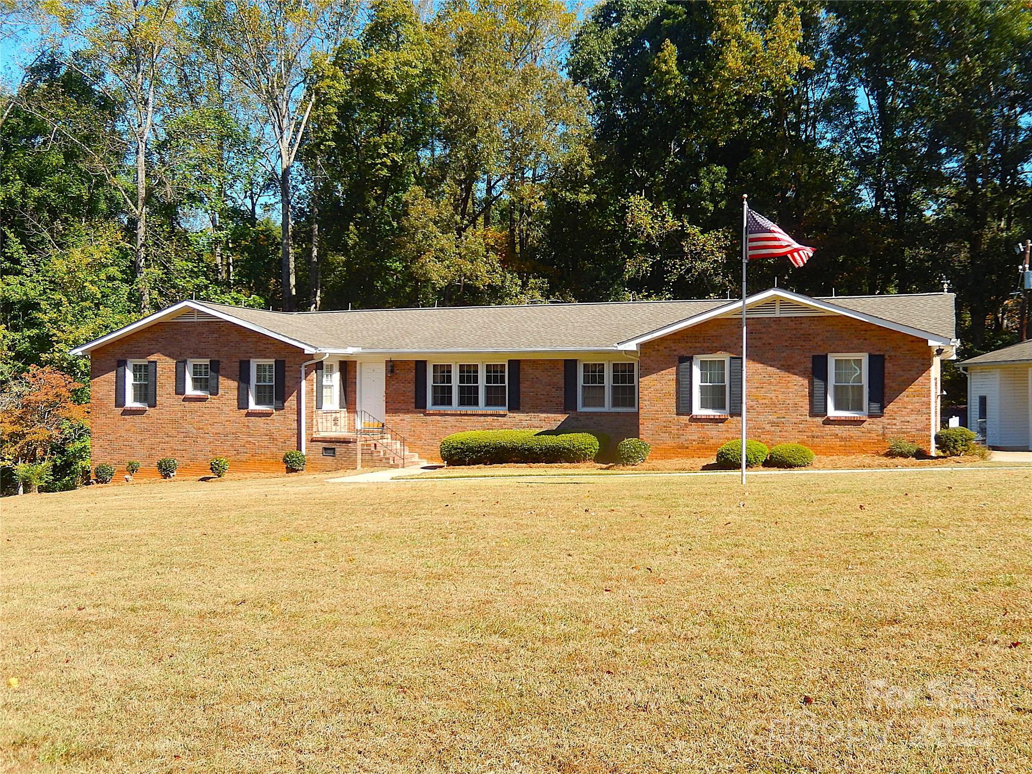 Located minutes away from Ballantyne and Blakeney in Indian Land, this one-owner full brick home has been well-loved since it was completed in 1973.  A classic home with an eat-in kitchen w/granite countertops & tons of cabinetry, a formal dining room & living room, and a comfortable den with gas log fireplace and a full masonry fireplace.  There are two spacious secondary bedrooms with an updated Jack & Jill bath.  The primary bedroom has a walk-in closet and the primary bath has double sinks and a pocket door to separate the vanity area from the toilet and bathtub/shower.   Gleaming hardwood floors in the kitchen, den, hallway, & both secondary bedrooms.  The primary bedroom, dining room, & formal living room are carpeted.   The den, both baths, and all bedrooms have plantation shutters on the windows.  The 810 sf basement has two partially finished rooms (drywall/ceilings) with carpet removed.  The rest of the basement is ready to be finished off, even including a rough-plumbed bath.  The basement is not being included in our HLA due to flooring, but is heated and cooled, and could realistically add another whole living area if finished.  Out back, there is a deck with a door directly into the den.   There is an attached 2-car finished garage with extra storage space leading into either the kitchen or the mudroom, and an oversized 2-car carport that was used for RV parking.  The carport also has an attached wired workshop!  Two additional storage buildings are located behind the carport.    This lot is FIVE acres, with the back portion being fully wooded.  The house sits up on the tallest portion of the lot.  A full home inspection was done on October 15, and the report is available from your agent or upon request.  As to be expected with a 50+ year old home, there are some repairs needed, and the property is priced accordingly.   The listing agent is also the executor of the estate.  No probate court approval is necessary for contract approval.  The home is livable as it is, but the new owner may choose to do some repairs and cosmetic updating.  The fridge is new in 2025.  The washer and dryer (included) are also recent (2019).  Other appliances are older, but still in fine working condition.   SOLD AS IS.  No repairs will be done.   Although we are not required to disclose this, no one ever died in the home.  You do not want to miss this opportunity to live so close to shopping, dining, and entertaining, with no HOA, and with the lower SC taxes!  This has never been a house.  It was always a very happy home!