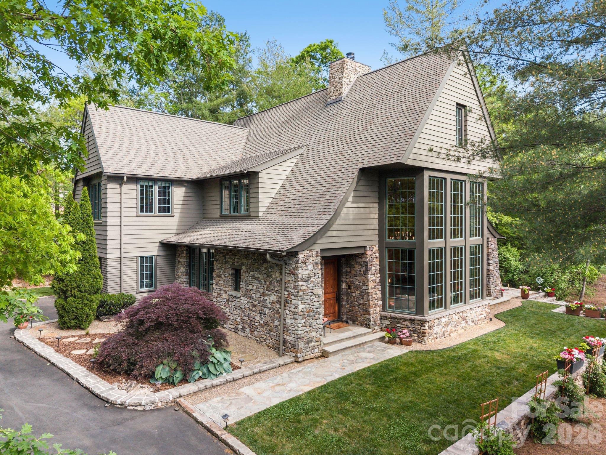 Tucked beneath a canopy of mature trees in the coveted The Ramble Biltmore Forest, 85 Chauncey Circle is a home that feels unforgettable from the moment you arrive. Designed by acclaimed architect Rob Carlton and thoughtfully constructed as a Certified NC Healthy Built Home, the residence seamlessly blends refined craftsmanship, wellness-focused design, and warm, livable spaces that invite both grand entertaining and everyday comfort. A custom front door opens to a stunning composition of soaring cypress-clad walls and ceilings, rich natural materials, and light-filled interiors, where exceptional craftsmanship and thoughtful architectural details unfold at every turn. At the heart of the home, the gourmet kitchen flows effortlessly into inviting gathering spaces anchored by a dramatic see-through stone fireplace. Walls of windows, custom cabinetry, and elevated finishes create a sense of understated luxury throughout. The main-level primary suite offers a private retreat, recently enhanced with a beautifully renovated bath, while upstairs features spacious guest accommodations with ensuite baths, a large family lounge with wet bar, and flexible spaces designed for hosting, recreation, and relaxation. Outdoor living is equally compelling, with a screened porch featuring a stone outdoor wood-burning fireplace overlooking the serene natural landscape that defines life in The Ramble. Recent improvements by the current owner—including fresh interior paint, updated lighting, electric blinds, new upstairs carpet, epoxy garage flooring, and an expanded asphalt driveway—bring a fresh, modern feel to this timeless home. Combining award-worthy design, Healthy Built certification, curated craftsmanship, and a coveted Ramble address, 85 Chauncey Circle is a rare opportunity to experience the very best of Asheville mountain living.