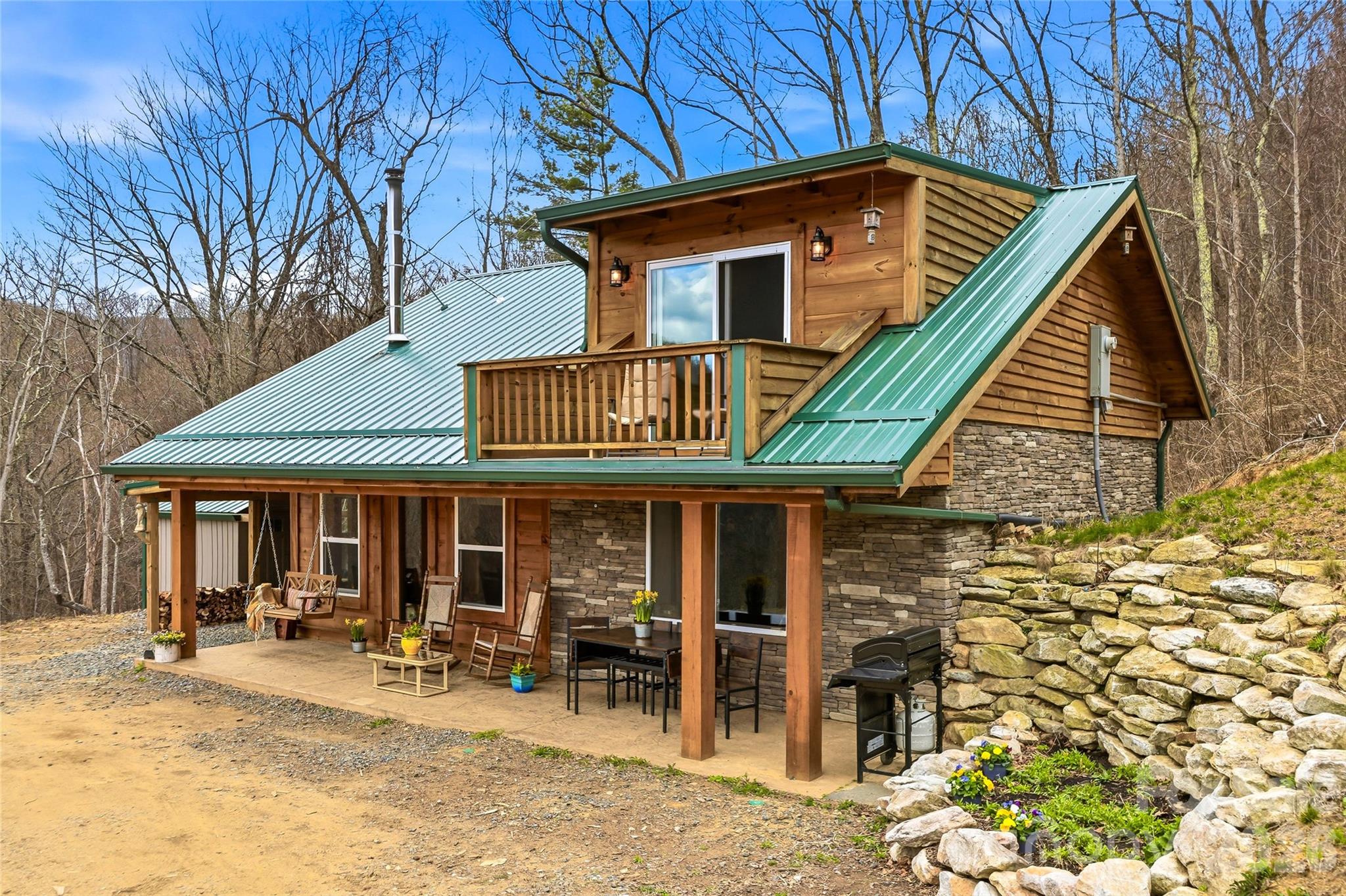 Inviting mountain cabin on 4.8± private acres, just 12 miles from Hot Springs, NC, offering exceptional privacy, natural beauty, and a rustic yet refined appeal. Surrounded by lush forest, this peaceful retreat provides easy access to the Appalachian Trail, hiking, rafting, and endless outdoor recreation. A picturesque waterfall along the road to the cabin enhances the serene mountain setting. An additional parcel is included—approved for a septic system and featuring a very nice natural spring—ideal for future building or preserving the view.

The home showcases quality timber construction and thoughtful craftsmanship, complemented by classic vintage-inspired hardware throughout. Designed to maximize its southeastern exposure, the cabin is filled with abundant natural light through well-placed windows. The living room centers around a cozy wood stove, creating a warm and inviting atmosphere. Two bedrooms on the main level are constructed with concrete block beneath the exterior stonework and interior wood finishes, offering both durability and character, while the upstairs loft provides flexible space with a half bath and private balcony—ideal as a sitting area, game room, or guest retreat—complete with breathtaking long-range mountain views.

Enjoy beautiful sunrises from the covered front porch, along with soft, refracted sunset views in the evening. The setting offers exceptional privacy, with no visible homes in the surrounding views, even at night. A striking creek with dramatic boulders and natural terrain enhances the landscape and creates a scenic boundary between properties. While not formally energy certified, the home has been constructed with efficiency in mind.

Unwind in the quiet tranquility of mountain living, all within easy reach of local dining, shops, and small-town charm.

Ideal as a year-round residence, weekend getaway, or income-producing vacation rental.