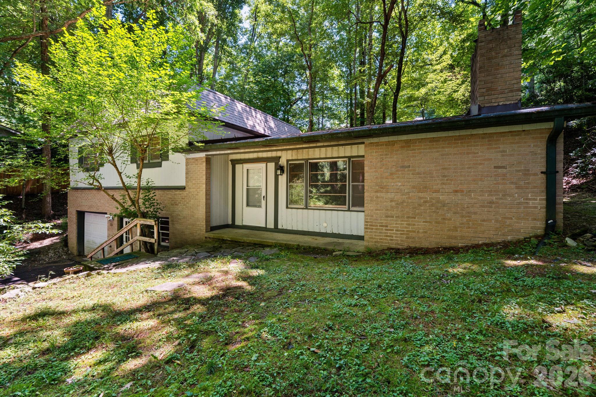 Sitting less than five minutes from the App State campus and downtown Boone, and just two minutes from Kidd Brewer stadium, this property offers a rare combination of convenience and opportunity at an accessible price point. This 1970 split-level home sits at the end of a short, shared driveway on a wooded 0.37-acre lot that provides a natural buffer from neighbors. Whether you are looking for a highly desirable student investment property or a solid starter home where you can build sweat equity, the location alone makes this a standout option. Inside, you enter a spacious living room anchored by a cozy woodstove fireplace and large picture windows that overlook a small grassy lawn, ideal for a firepit & outdoor dining set. The main level also features a separate den or dining area and a tidy, functional kitchen. Upstairs, the layout includes three bedrooms and two full baths. While plenty of opportunities remain to make this home your own, the big-ticket items have already been handled for you. The seller invested in a new roof and a new heat pump in 2025, and recent luxury vinyl plank flooring runs throughout the home. For added convenience, the property is connected to city water, sewer, and trash collection. The lower level is a major bonus, featuring an oversized one-car garage with over 800 square feet of space perfect for a workshop, gear storage, or a fitness area. This space includes a separate laundry and utility room, and an extra refrigerator that conveys with the sale. The property is being sold as-is. Buyers should note that a buried fuel tank on-site was properly decommissioned and filled with sand circa 2005, and a damaged sewer line was replaced at front of garage in June 2026 (all proper permits were pulled). Additionally, the seller reports water seepage under the garage door during heavy rains– it’s possible that the solution may be as simple as replacing the bottom weather stripping. If you want to be close to everything Boone has to offer, schedule a showing before this one is gone.