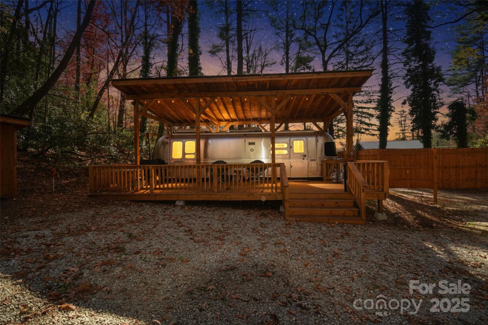 NEW PRICE, even better value! Discover 1.07 acres of nearly flat, raw buildable land in the heart of Sapphire, NC—Transylvania County's mountain gem. This parcel is primed for your vision, featuring a shared well and permitted 2-BR septic system installed for seamless development. A gentle stream meanders through, adding subtle natural charm. Access is effortless off US Hwy 64 via a private driveway that loops behind a full privacy fence, ensuring seclusion amid surrounding woods. Just minutes to Gorges State Park, Lake Toxaway, and Cashiers.
Ready for immediate enjoyment: A pristine 2013 30' Flying Cloud Airstream sits hooked up and waiting, complete with a large, separately built deck spanning its full length. A sturdy roof shelters both the camper and deck from the elements. The setup boasts dual 30-amp and 50-amp electrical service, plus convenient water spigots—all utilities connected for instant use.
Adjacent to the Airstream is a cleared area with an established firepit, ideal for cozy stargazing evenings. Separately, a large cleared space offers endless potential for gatherings—envision picnic tables, a gazebo, or your creative ideas. Plus, three pre-cleared tent sites make this ideal for a campsite business, glamping retreat, or endless outdoor ventures.
Rare unrestricted property: Perfect for your new home, weekend getaway, savvy investment, or entrepreneurial dream.