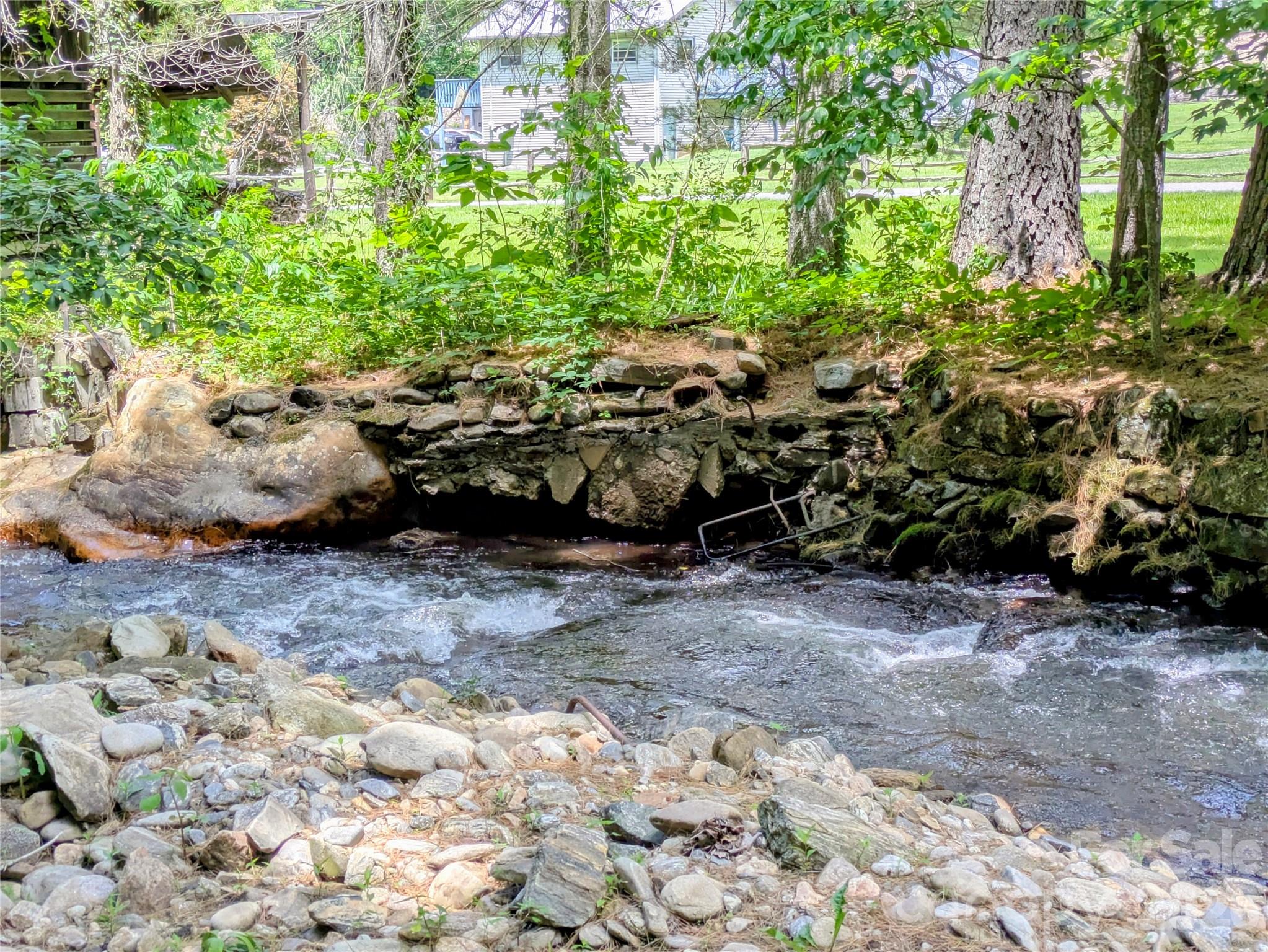 Did you ever say "I wish I had bought land here 25 years ago"?  Well this is your chance!  Absolutely amazing 2.25 acre parcel, NO RESTRICTIONS conveniently located just minutes away from all the conveniences of shopping and dining, yet all you will hear are the soothing magical sounds of sparkling water rushing over smooth stones and the songs of native birds. No damage from Helene. Over the years, the owners have manicured gently sloping paths that pause now and then at sunlit grassy clearings, some planted with fruit trees, and continue leading down until you reach the creek, which will take your breath away. With over 500 feet of creek frontage, you could wander in nature for hours. Up by the road is a level space perfect for a travel trailer or RV, and guests of the owners have stayed there frequently. Water and electricity are currently supplied to RV site  by adjoining property at 583 Dark Ridge Rd, MLS #4394353.  Steep slope assessment has been requested from the county and will be uploaded to documents when received.  Don't miss this once in a lifetime opportunity to live by that babbling brook you have always dreamed about, have a huge garden, raise chickens, and truly live the mountain lifestyle we all came here for.  House and additional 1.18 adjoining acres also for sale (MLS#4394353)  Additional 3.85 acres across the street (MLS #4394738) also for sale.  Don't miss this once-in-a-lifetime opportunity!  Showing appointments are required for all three listings - please contact listing agent.  No unsupervised showings.