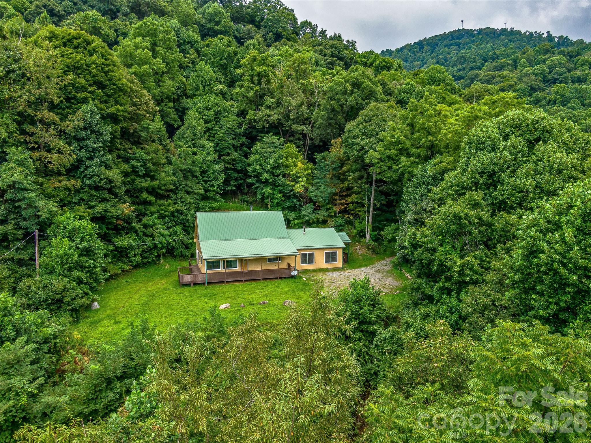 Tucked behind a gated private road at over 3,000 feet in elevation, this 35-acre mountain sanctuary offers a rare combination of seclusion, usable land, and designed-for-living comfort. A trail system follows old logging roads through your own forest, past a natural mountain stream, to clearings with layered mountain views that shift with the seasons.  

The 1.5-story cabin — 3 bed, 3.5 bath, 2,138 sq ft, built 2003 — centers around a floor-to-ceiling stone fireplace that anchors the open living space. A covered front porch extends the living area outward, where mornings start with coffee and end with stars. The main-level guest suite provides private accommodations for visitors or a dedicated workspace, while a stairlift ensures every level of the home is accessible.

Practical details are handled: metal roof, central air, well water, 4-bedroom permitted septic, attached garage. Protective CCRs preserve the character of this small mountain community — no short-term rentals, no drive-by traffic, just residents who value privacy and space.

Perched above the noise, yet grounded in comfort. This is mountain living, refined. Back on the market — the previous buyer's personal circumstances changed, creating a fresh opportunity to claim this remarkable property.

Appointment required for all showings. No drive-bys.