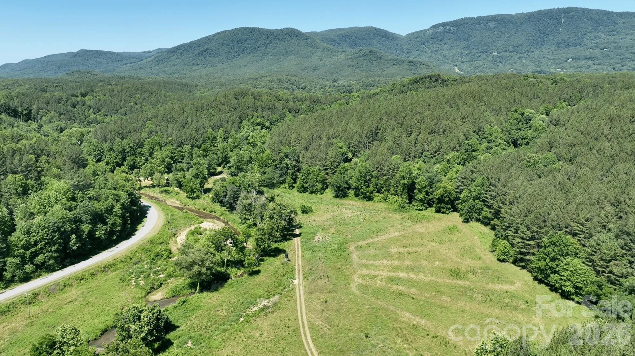 Perfectly set on nearly 350 acres of prime mountain land, Watermill Farm represents a rare opportunity to acquire a special large tract in the foothills of the Blue Ridge, just minutes from the neighboring Bright's Creek community and golf course. The namesake historical water wheel welcomes you into this exceptional property that features two 2-bedroom, 2-bath homes, buried power infrastructure, multiple pocket pastures, springs and creeks, abundant wildlife, and an existing network of well-maintained roads providing easy access throughout from the paved public road. The land offers a remarkable combination of privacy, usability, and development potential. Multiple broad knobs and ridge tops provide outstanding homesite opportunities, where selective clearing will reveal breathtaking long-range mountain vistas. Re-open extensive (but partially overgrown) pocket pastures to create an extraordinary equestrian property. Potential views of the Blue Ridge Escarpment are truly spectacular and could rival some of the finest in the region. The choice location is a short drove from the Green River, Lake Adger, Hendersonille, Tryon Int'l Equestrian Center, and more. Whether envisioned as a private mountain estate, family compound, recreational retreat, equestrian property, land investment, or future development opportunity, this unique offering combines natural beauty, existing infrastructure, and exceptional accessibility in one of Western North Carolina’s most desirable locations.