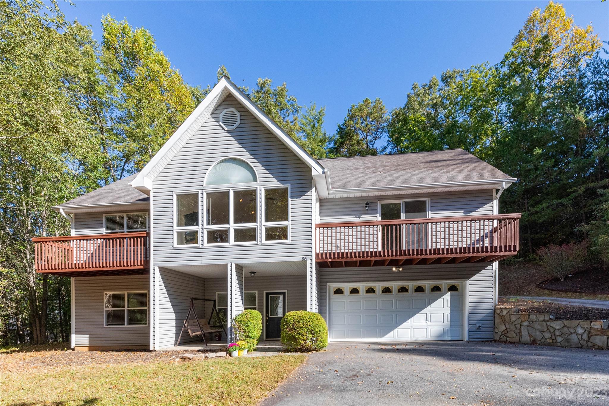 Spacious home nestled in gorgeous wooded Weaverville setting of Little Flat Creek subdivision! The main level of this home features a primary bedroom with ensuite bath and its own private balcony. 2 additional bedrooms, guest bathroom and open concept living/dining/kitchen round out the main level of this home. The great room has floor to ceiling windows that let in an abundance of natural light along with a gas fireplace perfect for the cool mornings and evenings ahead. The lower level has its own private bedroom suite, foyer, laundry room, and a bonus room currently being used as an exercise room. An oversized two-car garage offers plenty of room for storage or a workshop. Conveniently located a few minutes from Weaverville shopping and downtown Main Street.