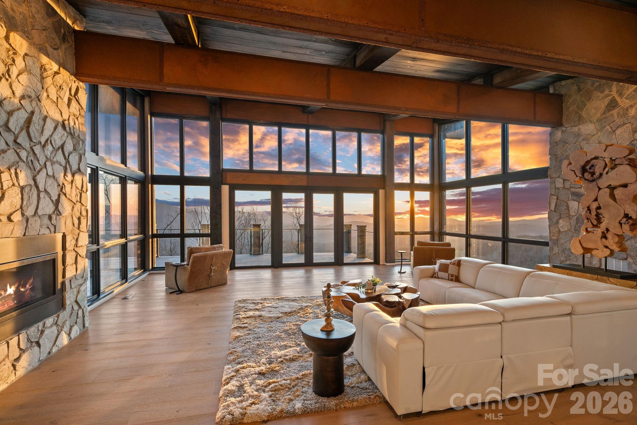 The Belvédère. Designed for the view. Built for the moment. 
Set high within Eagles Nest, this modern mountain retreat captures the kind of long-range, layered Blue Ridge views that rarely come available. Positioned within the community’s coveted Sunset Section, this home is oriented to take full advantage of golden hour, where the ridgelines glow and the sky settles into a nightly show that never repeats itself. 
At over 4,000 feet in elevation, mornings begin above the clouds and evenings transition into unobstructed sunsets stretching across state lines. 
Situated on approximately 1.2 acres, the home offers nearly 5,000 square feet of thoughtfully designed living space, with floor-to-ceiling glass framing the landscape from nearly every room. Natural materials including white pine ceilings, exposed beams, and stone accents bring warmth and balance to the modern architecture. 
The kitchen is both functional and refined, centered around a marble waterfall island, premium appliances, and a layout designed to flow seamlessly into the main living and dining spaces. The primary suite on the main level is quietly tucked away, offering a spa-like bath and uninterrupted mountain views. 
The lower level is built for hosting, complete with a custom bar, media and game space, and additional guest accommodations. Expansive covered decks extend the living experience outdoors, anchored by a hot tub and multiple vantage points to take in the surrounding ridgelines. 
Extensive landscaping, integrated lighting, and carefully placed stonework create a strong sense of arrival while maintaining a natural, elevated setting. 
Ownership here extends beyond the home itself. Within Eagles Nest, a private, gated mountain enclave, residents have access to a curated collection of amenities designed for a more refined outdoor lifestyle. Enjoy private access to the Elk River for world-class trout fishing, dining at Epic Chophouse, and gathering at the Sportsman’s Lodge. The community also features a private winery, miles of maintained UTV and hiking trails, a state-of-the-art fitness center, outdoor amphitheater, and even a dedicated helipad for seamless arrival and departure. 
This is a setting built for those who value privacy, access, and experience at a higher level. 
A rare opportunity to own a true view-driven property in one of the most sought-after sections of Eagles Nest.