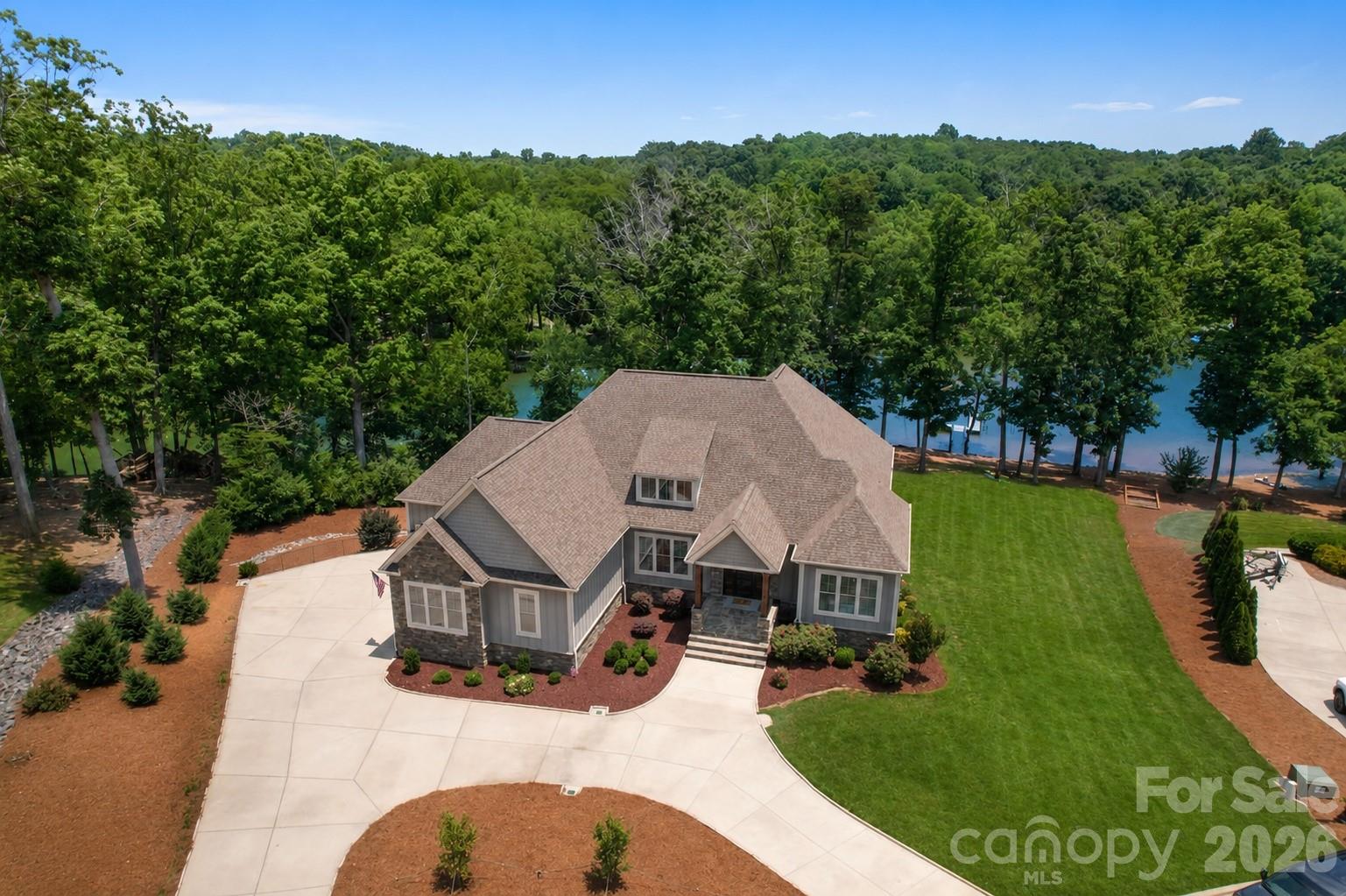 Some homes check boxes; this one redefines what lake living looks like.

Set on a private cove along the shores of Lake Wylie, this custom-built waterfront estate delivers a lifestyle most reserve for vacation. Except here, it's part of everyday life. Spanning 4,550 square feet of thoughtfully designed living space, the home is defined by soaring 10-foot ceilings, rich 5-inch hardwood floors, and uncompromising attention to detail.

The open floor plan is anchored by a dramatic great room featuring coffered ceilings and double doors that open directly to a spacious screened porch — your front-row seat to the tree-lined cove. The kitchen serves as a true centerpiece, boasting a large seating island, custom cabinetry, a gas cooktop, double ovens, a vent hood, built-in microwave, and granite countertops accented by a subway tile backsplash. Whether enjoying a quiet morning coffee in the sunny breakfast room or hosting an evening gathering around the island, this home was designed to bring people together.

The main-level owner's suite earns every square foot. Crowned by a triple tray ceiling, it offers a private sun deck with unobstructed lake views, an oversized walk-in closet, and a bath complete with a freestanding soaking tub and marble tile shower — thoughtfully positioned so that even stepping out of the shower offers a picturesque lake view, one of those details you only truly appreciate once you live here. Completing the main level is a dedicated home office and a guest bedroom with a private full bath, perfect for remote work or hosting out-of-town visitors.

Downstairs, the lower level adds exceptional flexibility and function. It features two additional bedrooms, a full bath and half bath, a cozy den, and a large recreation room anchored by a stone bar with a wine fridge. A standout feature is the custom bunk room crafted by local artisan Jon Kelly of Carolina Reclaimed. Functioning as a complete second living space, the lower level works beautifully for multigenerational households, long-term guests, or simply spreading out. An incredibly large storage room adds even more functionality and flexibility to the space.

Step outside to close to an acre-sized, flat lot where mature trees line the shoreline, providing a rare sense of natural privacy on the lake. Layered outdoor living spaces, including the screened porch, sun deck, lower-level patio, and fire pit area, flow effortlessly from inside to out. A stroll down to the boat dock places you directly on the water in a quiet cove with no through traffic.

A three-car garage, circular driveway, tankless water heater, and extensive finished storage round out a home that was built to live in, not just look at. Lake Wylie is one of the Carolinas' most sought-after lakes, and this exceptional property puts you right in the heart of it.