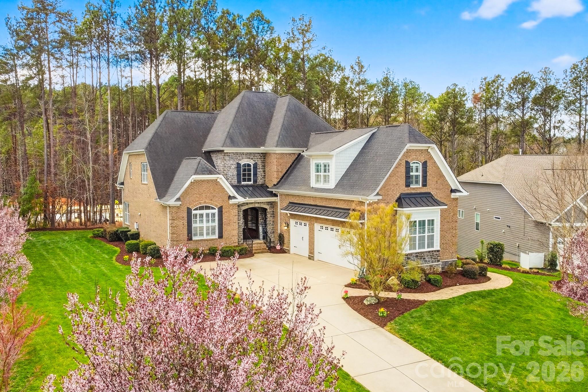 Welcome to 407 Blue Bay Court — tucked away on a quiet cul-de-sac inside the gated waterfront community of Handsmill on Lake Wylie, this home delivers the rare combination of privacy, space, and true “lake life” convenience. From the moment you arrive, the curb appeal and inviting front porch set the tone for a home that’s been thoughtfully designed for everyday comfort and effortless entertaining.

Inside, the main level is bright, open, and built around connection. The kitchen is a standout with a large island that offers extra storage (the kind you’ll actually use), plenty of prep space, and room for seating so everyone naturally gathers here. The kitchen flows directly into the large living room where a fireplace anchors the space and creates a warm, welcoming vibe. Whether you’re hosting a crowd or enjoying a quiet night in, this main living area feels spacious, functional, and filled with natural light.

The primary suite on the main floor is a true retreat. It’s generously sized with a huge window that pours in sunlight, and it offers direct access to a screened porch—perfect for morning coffee, evening wind-down time, or simply enjoying the peaceful, wooded backdrop. The primary bathroom features both a garden tub and a separate stand-up shower, creating a spa-like setup. A major bonus: the primary closet connects straight to one of the home’s two laundry rooms (yes—two), making daily routines smoother and laundry far less of a chore. A convenient half bath on the main level adds functionality for guests.

Upstairs, you’ll find additional large bedrooms with the kind of space that works for families, guests, teens, or multi-generational living. One of the standout spaces on the upper level features floor-to-ceiling warm shelving—perfect for a home library, office, reading room, or display space for collections. With additional flexible space upstairs, you also have options for a bonus room, playroom, media area, or a quiet retreat separate from the main living areas.

Step outside and you’ll see why this homesite feels special. The backyard is private, wooded, and beautifully framed by trees, creating a calm, tucked-away atmosphere. A deck expands your outdoor living space—ready for grilling, entertaining, and enjoying Carolina evenings with plenty of room to relax.

Lake Wylie lifestyle deserves its own spotlight: living here means you’re minutes from the water and the kind of weekends people move for—boating, kayaking, fishing, sunset rides, and meeting friends lakeside. The Lake Wylie area also offers an easy mix of outdoor recreation and everyday convenience, with nearby dining, marinas, and shopping close enough that you can enjoy the lake vibe without feeling far from essentials.

Handsmill takes that lake lifestyle and adds a resort-style feel right at home. Behind the gates, residents enjoy a true neighborhood experience—places to meet friends, stay active, and unwind—whether that’s an afternoon by the pool, time in the fitness center, an evening walk on the sidewalks and trails, or easy access for your boat and lake days. It’s the kind of community that makes it simple to get outside more, be social when you want to be, and still come home to privacy.

If you’ve been searching for a home that offers a premium floorplan, a standout primary suite, indoor-outdoor living, and access to the Lake Wylie lifestyle in a gated community, 407 Blue Bay Court is the one to see.