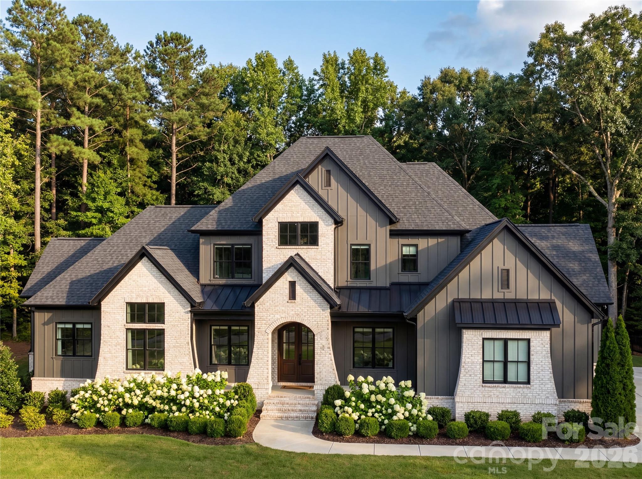 You know the house on the street that makes you slow down and look twice? This is that house.
612 Wisteria Vines Trail is brand new construction by OZ Custom Homes in Fort Mill's Wisteria Meadows community.
4,173 heated square feet with a main-level owner's suite, a second bedroom downstairs, a dedicated office, and a two-story foyer that hits different when the afternoon light comes through. The kitchen flows into the dining room and family room the way it should — open, easy, built for the way you actually live. White oak hardwood floors run throughout. A gas fireplace grounds the living space. Premium cabinetry, designer countertops, and a tankless water heater with recirculating pump because lukewarm isn't luxury.
The finishes tell the story — solid core 8-foot doors on every level, 7-inch crown molding, custom tile work, and shower doors that feel like they belong in a boutique hotel. Lighting allowance alone is $25K. This isn't builder grade anything.
Upstairs gives you another 1,173 square feet of breathing room. And below? A 3,000 square foot unfinished basement that's basically a dare. Home theater. Gym. Wine room. Go crazy.
Outside, it's James Hardie board and batten with brick accents, standing seam metal details, and an arched entry that stops people mid-scroll. Covered porches front and back. Three-car garage because you've earned every bay. One acre lot provides more than enough space for a future pool and outdoor oasis.
Now here's where it gets really good. Wisteria Meadows is minutes from Lake Wylie and right around the corner from The Grove at Tega Cay — the $250 million mixed-use development bringing walkable dining, shopping, and lifestyle to the area. Fort Mill schools. Tega Cay water and sewer. You're not just buying a home, you're buying into what's next.