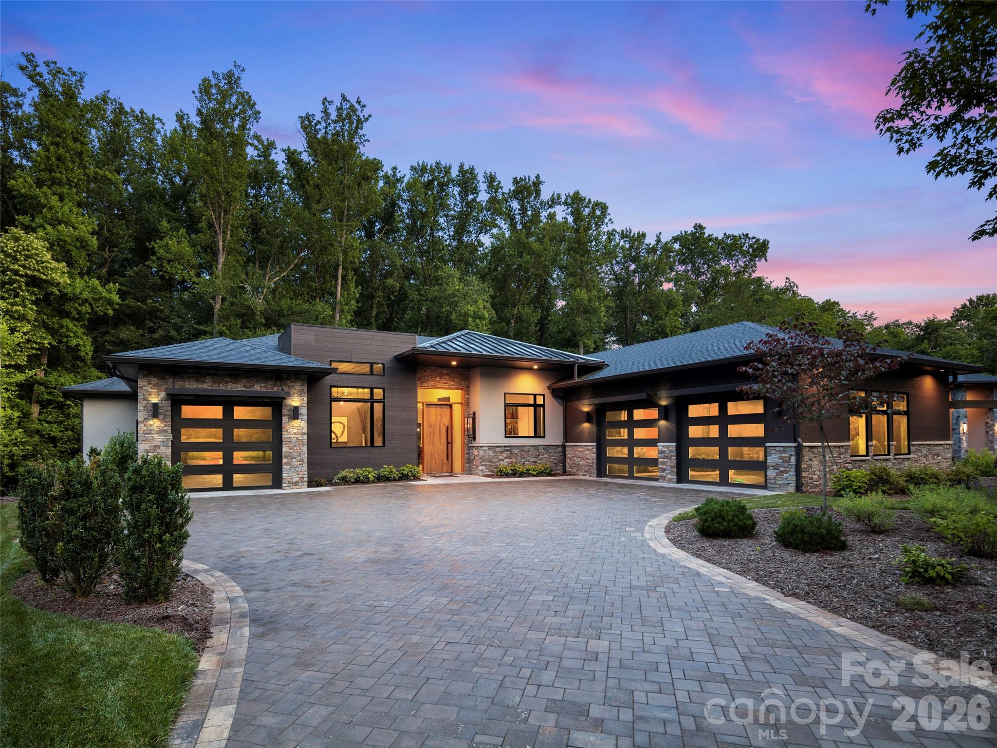 This spectacular one-level contemporary masterpiece at 26 Whispering Bells Court offers the pinnacle of luxury living within The Cliffs at Walnut Cove. Inside, an abundance of strategically added windows floods the open floor plan with radiant natural light. The chef's kitchen is anchored by a sophisticated double-island configuration, pairing a porcelain-topped main island with a secondary island crafted from pristine quartz. Premium porcelain extends across all other perimeter countertops and the matching full-height slab backsplash, flawlessly unifying the culinary workspace. Effortless indoor-outdoor entertaining is realized through zero-entry accordion doors that open completely to a magnificent screened lanai, beautifully designed with integrated heaters and added skylights for a bright, all-season sanctuary.

The primary suite serves as a completely private oasis, designed with unmatched attention to detail. The spacious bedroom is uniquely elevated by custom integrated curtains, and features an elegant built-in bed that remains with the home. Beyond the sleeping quarters, the showroom-style walk-in closet is a masterpiece of organization, complete with a custom center island and a highly convenient secondary laundry setup. The spa-like ensuite bath offers a true retreat, boasting a sleek zero-entry shower and a premium Bain Ultra heated freestanding soaking tub, creating a flawless and tranquil space to unwind.

The home is equally well-appointed for family or guests, offering two bright and spacious bedrooms, each featuring its own private bathroom and generous closet storage. Daily functionality is seamlessly integrated with a full main laundry room featuring dedicated vacuum storage, complemented by ample storage closets throughout the hallways. The flawless floor plan is complete with a sophisticated den perfect for a private home office or media room, as well as dual garages that provide pristine accommodation for multiple vehicles and extra gear.
With a membership at The Cliffs, residents enjoy a world-class lifestyle centered around an 18,000-square-foot wellness center featuring indoor and outdoor pools, tennis courts, and a luxury spa. The community's crown jewel is a Jack Nicklaus Signature golf course, complemented by an award-winning clubhouse and "The Tavern" social hub for fine dining and member events. Bordering the Pisgah National Forest just minutes from the Blue Ridge Parkway and Asheville, this community offers a rare combination of high-altitude privacy and premier convenience.
