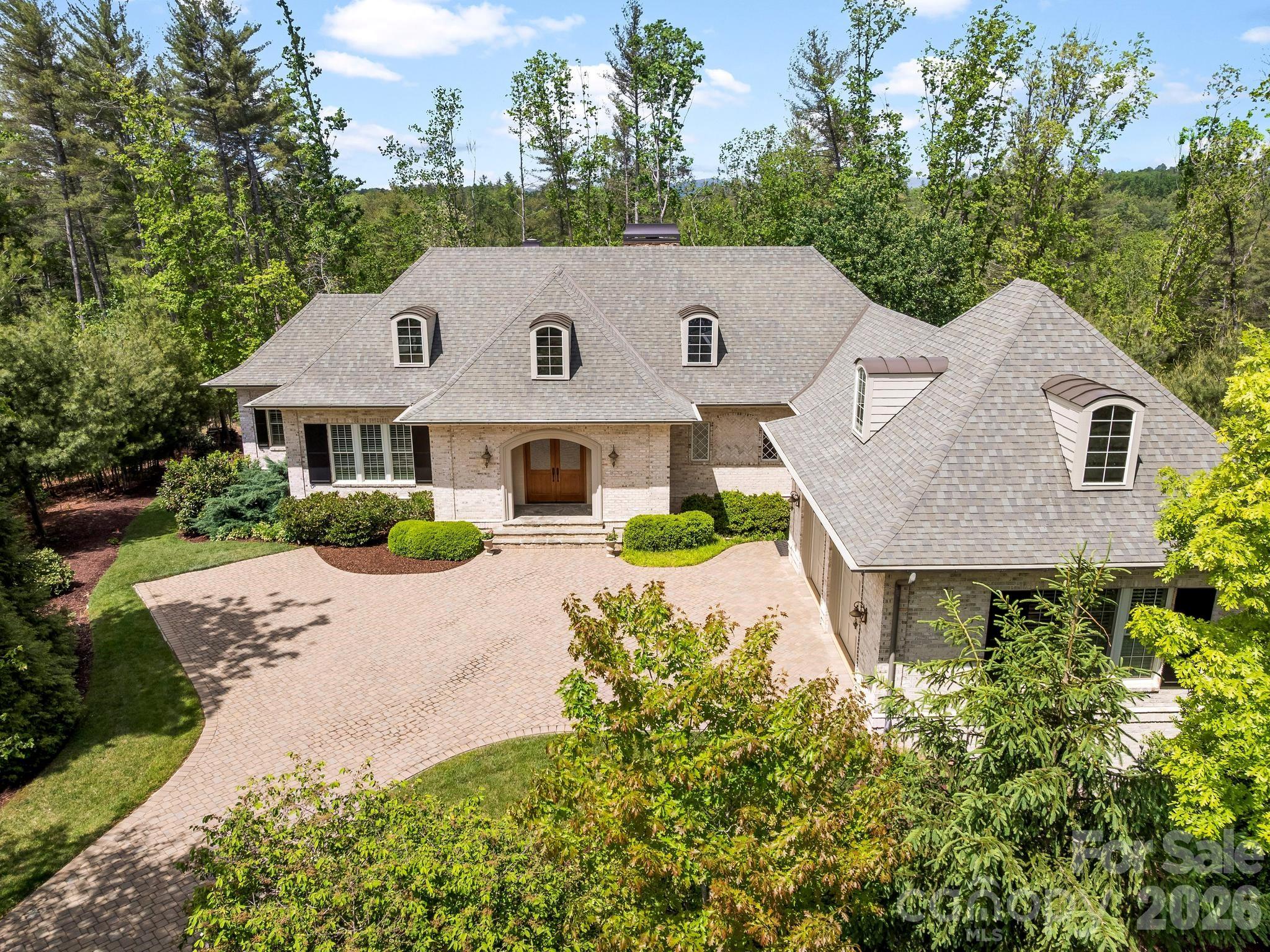 Welcome to this French country inspired home in the heart of south Asheville! With its casual elegance and inviting appeal, it is ideal for those seeking a home that is both comfortable and stylish. Nestled at the end of a quiet cul-de-sac, the home features authentic brick construction and flagstone entryway. Inside, a spacious kitchen, dining and sitting area emphasize comfort and functionality. The double-sided fireplace provides warmth and ambiance. Three sets of French doors open onto a spacious, fully screened porch, enhanced by ceiling fans and skylights. The primary bedroom boasts a gas fireplace and relaxing ensuite bathroom with spacious walk-in shower, soaking tub and double vanities. A private office is conveniently situated on the main level, while an additional guest suite and two bedrooms on the lower level offer flexible options for living space. The walk-out patio opens to a private backyard next to community greenspace. Modern heating systems, high-quality insulation, and a generator ensure comfort and peace of mind year-round. For added convenience, the home includes surround sound, two dishwashers, two washers, two dryers, energy-efficient tankless hot water heaters and a whole-house water filtration system. Plus, a large unfinished storage area can be finished into a home gym, theatre room or extended living space. This blend of practical amenities, modern comforts, and elegant design creates a refined yet comfortable retreat in a truly beautiful setting.