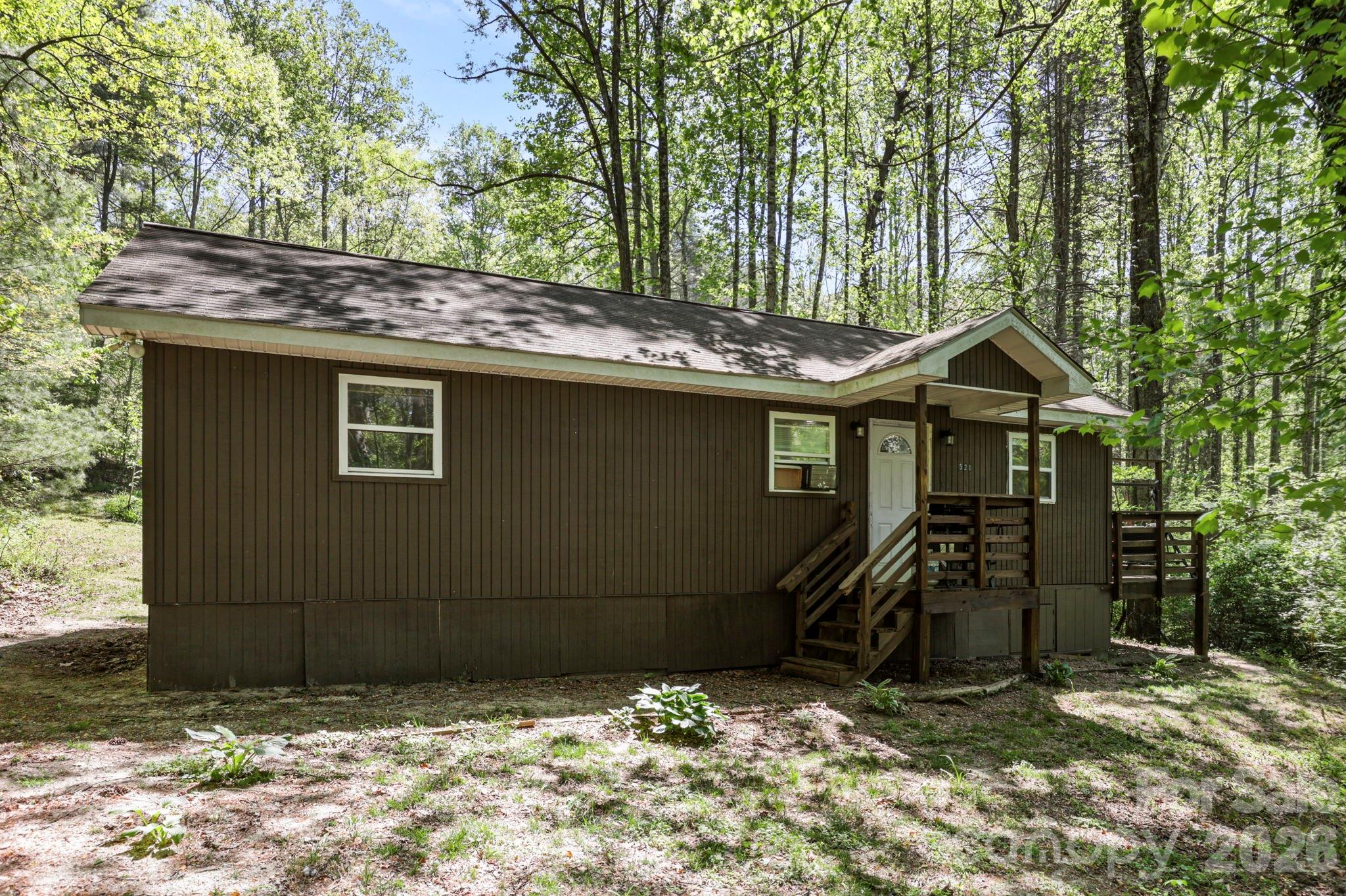 521 Lake Falls Road is set on 1.08 wooded acres in a quiet pocket between Hendersonville and Flat Rock, offering a balance of privacy and convenience. With no restrictions and frontage on a publicly maintained road, the property allows for a range of uses with easy year-round access.

The home is move-in ready with two bedrooms and one bath, offering a comfortable and efficient layout. It has a natural charm that suits the setting—uncomplicated, inviting, and easy to care for. With no restrictions, it lends itself well to a full-time residence, a seasonal retreat, or a rental opportunity.

Location is a key part of the appeal. Camp Ton-A-Wandah sits directly beside the property, and the surrounding Flat Rock area is known for its quiet character, historic homes, and longstanding summer traditions. The Flat Rock Playhouse and the Carl Sandburg Home are both just minutes away, adding to the cultural backdrop of the area.

Everyday conveniences are close at hand. Downtown Hendersonville is approximately 6 minutes away, with multiple grocery stores, restaurants, and local shops, making it easy to access everything you need without sacrificing the quieter setting.

A simple, well-located home in an established area known for its character, history, and easy access to both town and nature.