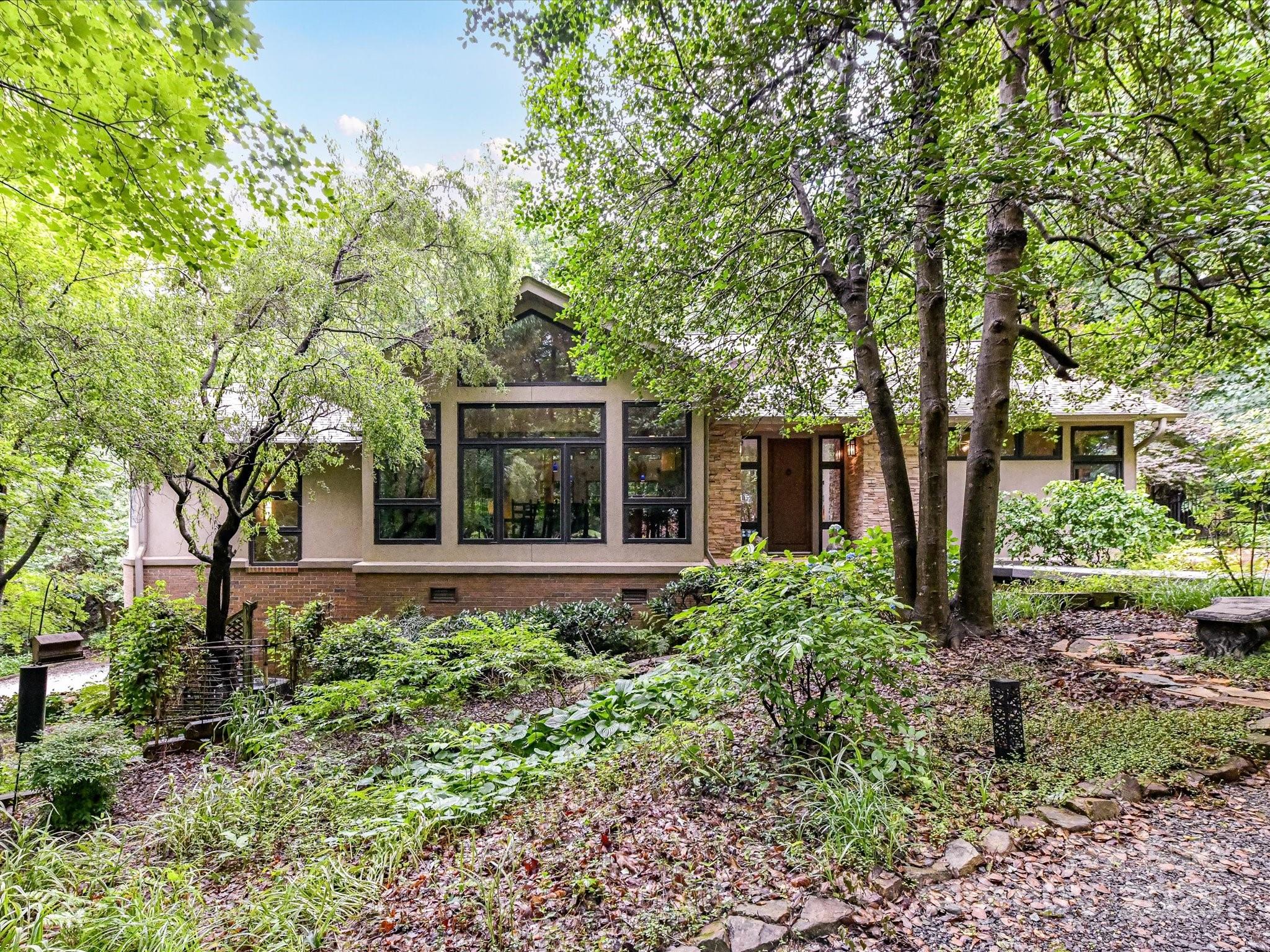 Tucked away in a peaceful, nature-filled setting yet minutes from shopping & dining off 521, this custom-built mid-century modern retreat offers timeless design & flexible living options on a 1.19-acre fenced lot. Inside, there is a striking circular foyer with a skylight, vaulted ceilings, & floor-to-ceiling windows. The heart of the home is a kitchen featuring a brand-new gas range, an island with seating, & custom cabinetry. The spacious primary suite includes a walk-in closet, while two additional bedrooms & a full bath offers privacy. One bedroom features a spiral staircase that leads to a loft with stunning views, which is ideal as a studio or office. Enjoy outdoor living from the screened-in porch or on the back patio, all surrounded by mature trees. The oversized two-car garage includes an attached workshop. A standout feature is the 456 sq ft second living quarters, complete with a kitchenette and full bathroom. As a bonus, residents enjoy access to a scenic pond.