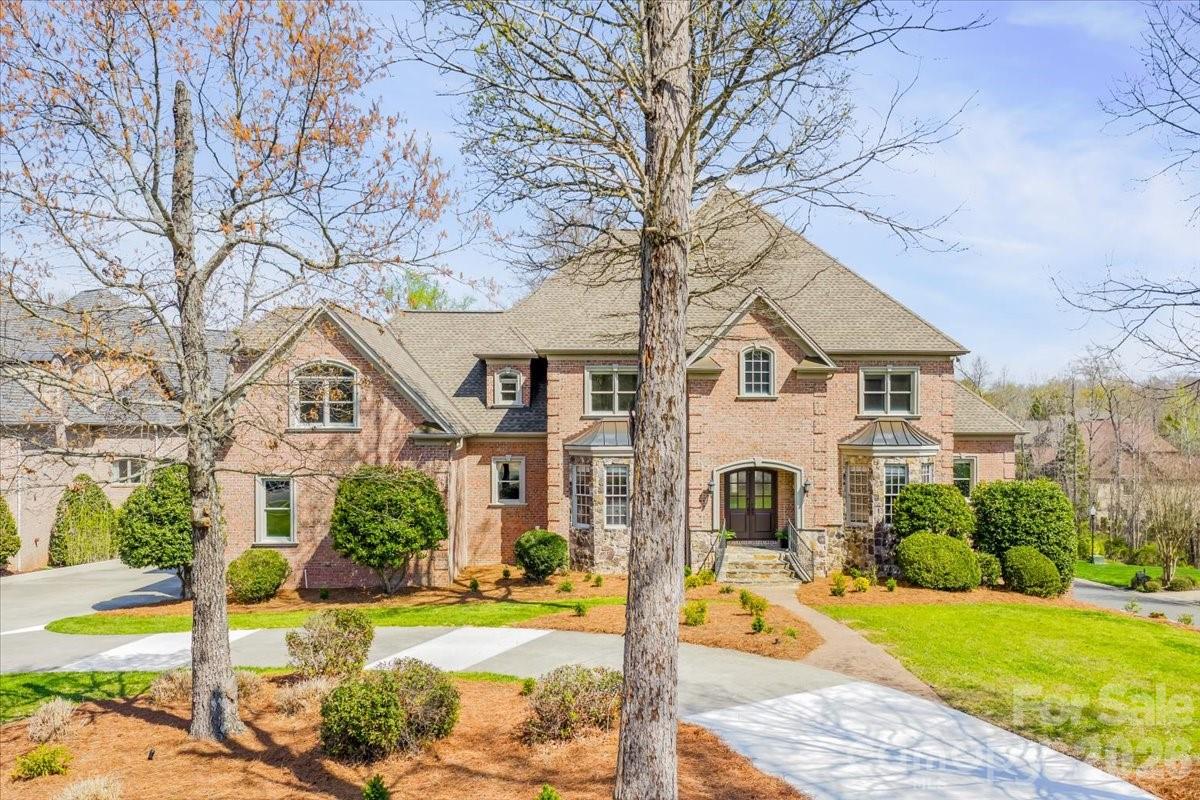 Introducing this exquisite custom-built luxury estate in highly sought-after Providence Downs South, where architectural elegance meets exceptional functionality. This all-brick masterwork offers an unparalleled level of privacy and sophistication. Step through the impressive arched double doors into a spectacular two-story foyer featuring classic travertine tile flooring, intricate wainscoting, and a gracefully curved wrought-iron staircase. Arched passageways lead to the spacious formal dining room, perfect for hosting grand gatherings. French doors open to a prestigious executive office complete with a rich wood coffered ceiling and gorgeous built-in bookshelves. The dramatic, vaulted great room boasts a massive wall of floor-to-ceiling windows and doors, anchored by a beautiful stone fireplace and custom built-ins. Culinary enthusiasts will admire the gourmet kitchen, which features cream-colored stacked cabinetry, a monumental dark wood contrasting center island, gleaming granite countertops, a Viking professional gas range, double ovens, and high-end panel-ready refrigeration. Extend your entertaining outdoors from the main level onto an oversized balcony, offering a serene vantage point overlooking the lush, private backyard. Designed for ultimate privacy and comfort, this home features 5 generous bedrooms plus a 6th bed/bonus room, with EVERY bedroom including its own pristine, dedicated full en-suite bath. An additional 2 elegant half-baths serve guests. Ascend to the versatile third floor, an expansive space perfectly suited for a vibrant game room, home gym, or secluded private retreat. The mudroom/utility room is equally impressive, with high-end cabinetry, granite counters, and a utility sink. The sprawling, finished walk-out basement is a destination in itself. Entertain in style with a dedicated movie theater featuring stadium seating, accompanied by a full professional bar. This level is also perfectly equipped as a private in-law or guest apartment, complete with its own second full kitchen, a spacious living area, and a private bedroom with a full en-suite bath. Step seamlessly from the basement out to a phenomenal paved back patio. This magnificent outdoor living area is built for year-round enjoyment, featuring both a built-in firepit and a stunning outdoor fireplace. Perfectly situated in the quiet elegance of Marvin, NC, this estate is a rare find, combining superior craftsmanship, abundant square footage, and a floor plan optimized for modern, high-end living.