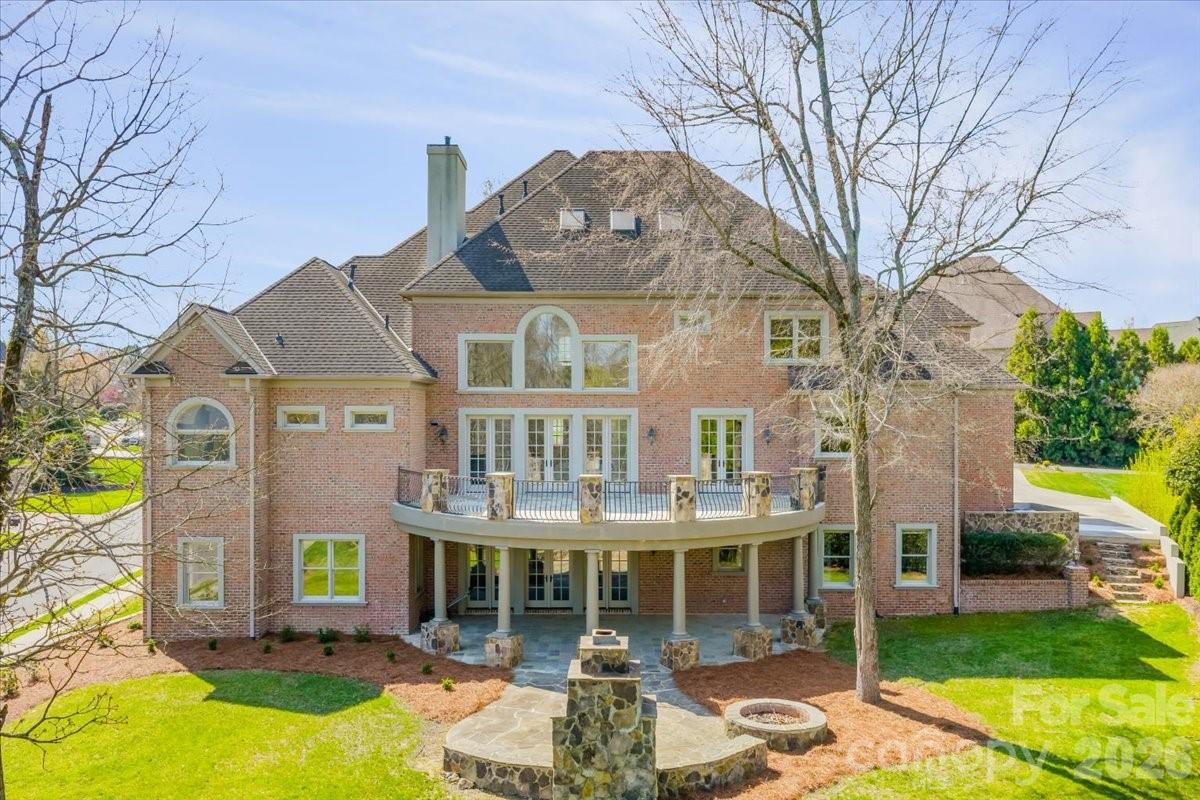 Introducing this exquisite custom-built luxury estate in highly sought-after Providence Downs South, where architectural elegance meets exceptional functionality. This all-brick masterwork offers an unparalleled level of privacy and sophistication. Step through the impressive arched double doors into a spectacular two-story foyer featuring classic travertine tile flooring, intricate wainscoting, and a gracefully curved wrought-iron staircase. Arched passageways lead to the spacious formal dining room, perfect for hosting grand gatherings. French doors open to a prestigious executive office complete with a rich wood coffered ceiling and gorgeous built-in bookshelves. The dramatic, vaulted great room boasts a massive wall of floor-to-ceiling windows and doors, anchored by a beautiful stone fireplace and custom built-ins. Culinary enthusiasts will admire the gourmet kitchen, which features cream-colored stacked cabinetry, a monumental dark wood contrasting center island, gleaming granite countertops, a Viking professional gas range, double ovens, and high-end panel-ready refrigeration. Extend your entertaining outdoors from the main level onto an oversized balcony, offering a serene vantage point overlooking the lush, private backyard. Designed for ultimate privacy and comfort, this home features 5 generous bedrooms plus a 6th bed/bonus room, with EVERY bedroom including its own pristine, dedicated full en-suite bath. An additional 2 elegant half-baths serve guests. Ascend to the versatile third floor, an expansive space perfectly suited for a vibrant game room, home gym, or secluded private retreat. The mudroom/utility room is equally impressive, with high-end cabinetry, granite counters, and a utility sink. The sprawling, finished walk-out basement is a destination in itself. Entertain in style with a dedicated movie theater featuring stadium seating, accompanied by a full professional bar. This level is also perfectly equipped as a private in-law or guest apartment, complete with its own second full kitchen, a spacious living area, and a private bedroom with a full en-suite bath. Step seamlessly from the basement out to a phenomenal paved back patio. This magnificent outdoor living area is built for year-round enjoyment, featuring both a built-in firepit and a stunning outdoor fireplace. Perfectly situated in the quiet elegance of Marvin, NC, this estate is a rare find, combining superior craftsmanship, abundant square footage, and a floor plan optimized for modern, high-end living.