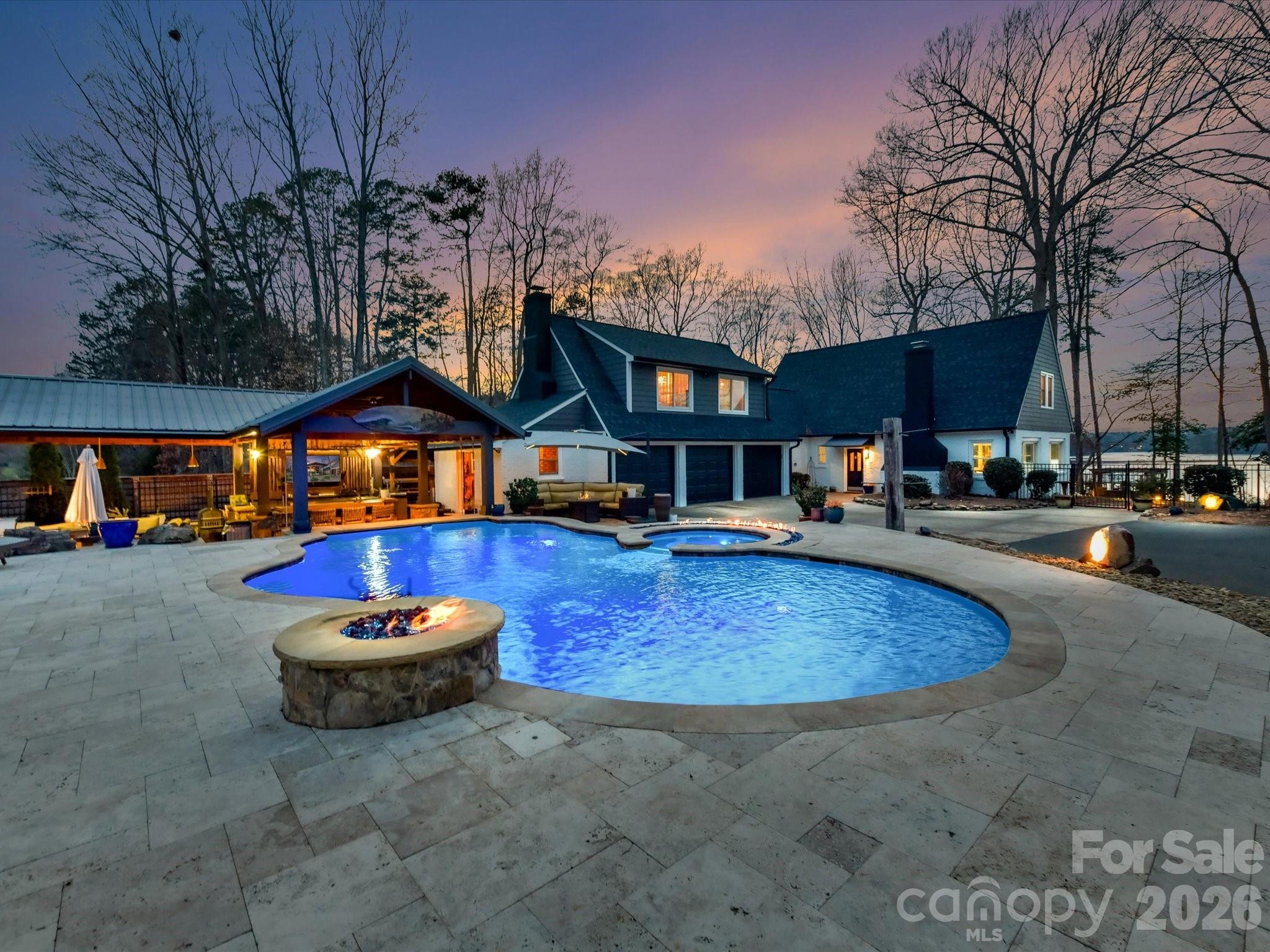 There are properties that you purchase, and there are properties that you arrive at — From the moment you turn onto Mountain Point Lane, the canopy of trees gives way to open water, you understand that this home is something entirely different. This is not a home that requires your imagination to fill in the lifestyle. It already exists here, fully realized, resort-complete, and waiting. The sense of having made it — truly made it — is built into every square inch of this estate. The lake greets you like a standing ovation every morning.
What anchors this property above all else is a view that cannot be bought on Mountain Island Lake. Panoramic sightlines stretch across the open water toward more than 1,500 acres of Latta Nature Preserve — permanently protected land that will never be developed, subdivided, or altered. What you see today is precisely what you will see in twenty years: open water, ancient hardwoods, and the kind of quiet Charlotte rarely offers twenty minutes from Uptown. This is the rarest of real estate luxuries — a view with a guarantee.
Step outside, and the resort experience begins without ceremony. A heated saltwater gunite-built pool and hot tub anchor the outdoor oasis, with expansive walk-in steps that invite you to ease into the water at any depth. Gas fire features flank a swim-up bar — submerged barstools included — creating an atmosphere that feels closer to St. Barts than suburban Charlotte. The oversized pool bath is finished with dual showers and ornate granite, designed to serve guests all afternoon without a trip back indoors. This is outdoor living elevated beyond the expected.
The dual outdoor kitchens are a statement of intent. Lakeside, a restaurant-quality setup awaits the host: gas griddle, commercial hood, warming drawers, and a full prep station capable of producing a dinner party from scratch. Poolside, a second kitchen keeps the energy flowing for casual cooking and effortless entertaining. Pair these with a guest cabana offering its own mini kitchen, a gazebo with dual water features, a wood-burning fire pit, and a lovingly tended herb and flower garden with an outdoor shower, and you have a property that entertains itself.
The double-decker dock is not an amenity. It is a destination. Newly constructed with Trex-style composite materials and a special Gutter Deck waterproofed upper level, cool underfoot even in the height of summer, the upper deck is purpose-built for morning yoga, sunset wine, or simply standing above the water. Below, a 10,000 lbs. capacity boat lift and a Rotomag jet ski lift rotate mechanically into position on demand to make lake access effortless. Extra-wide stairs accommodate kayaks and paddleboards. A dedicated golf cart path connects the home to the dock without stepping through wet grass, and a lakeside landing with a porch swing ensures there is always one more reason to stay outside a little longer.
The interior is designed for real life. A chef’s kitchen, artisan-bleached stonework great room, white-washed shiplap ceiling, and an open layout that flows the way a well-lived home should. Four bedrooms, three and a half baths, and 3,239 square feet that feel generous because every room connects seamlessly. Warm, refined, and livable — the interior is the quiet counterpart to the pageantry outdoors.
The outdoor infrastructure at 5401 Mountain Point Lane — dock, lifts, pool system, fire features, dual kitchens, cabana, gazebo — represents your investment in lifestyle experiences that simply cannot be replicated elsewhere on this lake at this price point. Layered in a permanently protected preserve view, 1.61 private acres on a rectangular lot, and a three-car garage— The price is not a premium. It is the only amount that exists for a home of this caliber. There is no comparison. There is no alternative. There is only this property, and the decision to experience it in person. Private showings available by appointment — schedule yours today.
