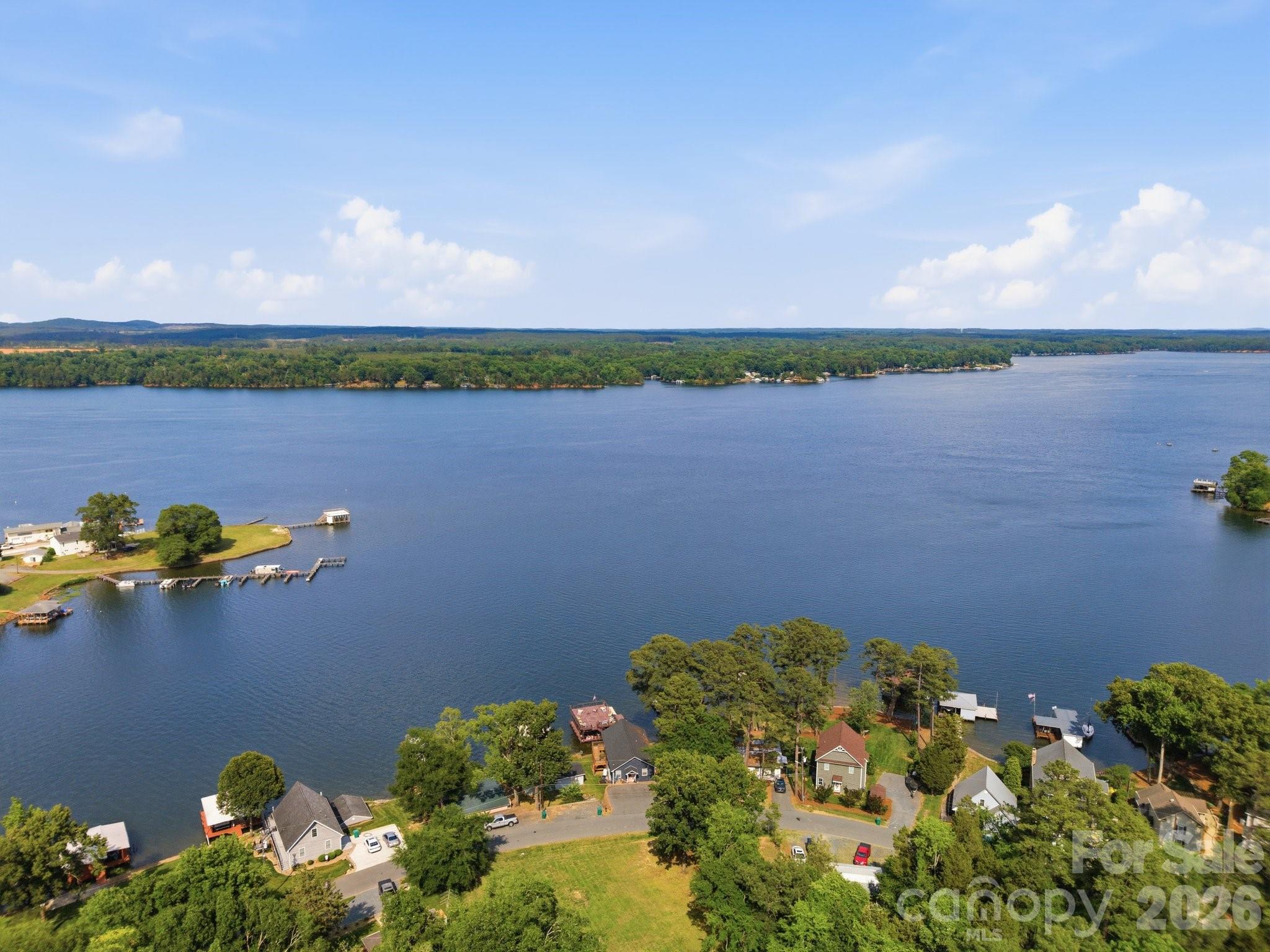Lake Tillery Main-Channel Waterfront with an Additional Lot Included!! Long-Range Views & Deep Water - Per Owner: A Spiral Staircase was factored in on the engineered plans, and this can be added; the current owner did not want to add them, the new owner can add a Spiral Staircase to connect the 2 floors if desired.
Experience Lake Tillery living on one of the most sought-after stretches of the Main Channel, offering some of the best long-range views on the lake. This property sits on a level shoreline lot, and per the seller, this lot has exceptional deep water—approximately 10' of depth behind the boat and approx. 6' at the pier. The waterfront features a covered double-slip boat dock with 2 boat lifts, a large open upper sun deck, an open pier with a retractable awning for shade, and a floating PWC with room for 2 jet skis. Whether relaxing, entertaining, or enjoying lake activities, this setting delivers the ideal combination of views, depth, and usability. The upper main level floor of the home was thoughtfully designed and newly built in 2023 to offer an open, airy lake vibe with expansive water views from the light-filled living, kitchen, and dining spaces, with windows oriented toward the water for exceptional lake views. You will enjoy cooking in this beautiful, modern kitchen while being a part of all the fun with connections to the open living and dining areas. What a view to take in, day or night, from the full-length covered and screened-in porch that overlooks the lake. The main upper level offers two well-designed bedrooms and a stylish full bath. Lower Level – Separate Living Quarters - The lower level remains from the original 1961 lake home, but it has been given many updates and provides a fully independent living space, ideal for guests, a studio, or potential rental income, offering a separate entrance, two additional bedrooms, a full bath, a living area, an entry room office/flex space, a full kitchen(existing stove will need to be replaced and hooked back up- the owners disconnected the current stove/oven), You will have access to the lower-level full-length covered porch and a separate laundry/utility room with hook-ups ready for a secondary washer/dryer, lower porch has ample sitting space with a spectacular view of the lake. The home renovation and construction were engineered to allow for a spiral staircase to be added in the future if interior access between levels is desired for the new owner. Additional Vacant Lot Is Included- A valuable asset for lake living, and a big bonus for lake properties—the additional lot is located across the street, offering extra parking for several vehicles, plus 2 storage buildings for lake gear, tools, golf cart, or yard equipment. This is a rare opportunity to enjoy “On Lake Time At Its Best,” where Stunning Main-Channel Long-Range Views meet truly effortless lake living with Deep Water Right Off The Dock. This is a modern home design offering flexible living spaces, an additional lot for parking, and a grandfathered Double Decker Boat Dock with 2 boat slips, each with lift and Upper Sundeck, a floating PWC room for 2 Jet Skis- This is Everything you want on Lake Tillery—and it's right where you want to be--Lake Tillery vibes are awesome here. List Broker is Related to the Seller