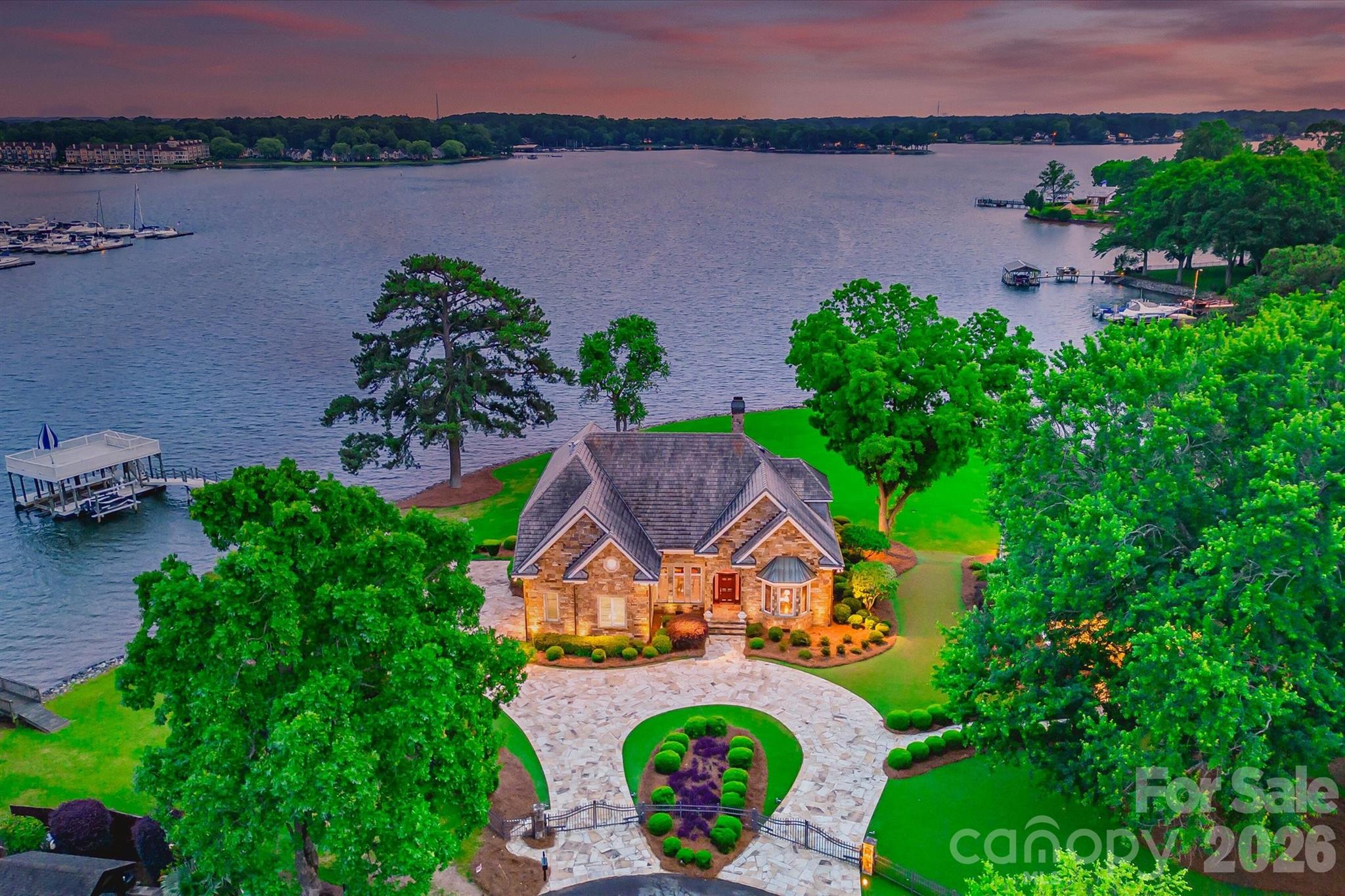 Positioned along a pristine shoreline on Lake Norman, this gated waterfront property offers a rare sense of scale, privacy, and uninterrupted water views. Set within a quiet cul-de-sac in Cornelius, the setting feels both tucked away and highly convenient—without HOA restrictions.

The residence is thoughtfully designed to maximize its connection to the lake, with expansive living spaces and large-scale windows that frame the water from nearly every vantage point. Each bedroom features its own private ensuite, offering comfort and privacy for both residents and guests. Interior finishes reflect a warm, timeless aesthetic, including cherry wood flooring and cabinetry, Pella windows, and custom craftsmanship throughout.

The waterfront experience is elevated by a distinctive double-decker dock, featuring a covered boat slip with lift below and an upper-level platform ideal for lounging, entertaining, or taking in the panoramic lake views. In addition, a dedicated lift accommodates two personal watercraft, creating a seamless setup for lake living. There is a well enforced no wake zone extending past the marina and as a result there is little or no noise generated from boats that are going in and out of the marina. It is one of the quietest lots on this side of the lake.

A separate guest house and additional lot are available for purchase, presenting an opportunity to further expand the estate if desired.

A distinctive Lake Norman offering that combines privacy, craftsmanship, and an exceptional waterfront setting.