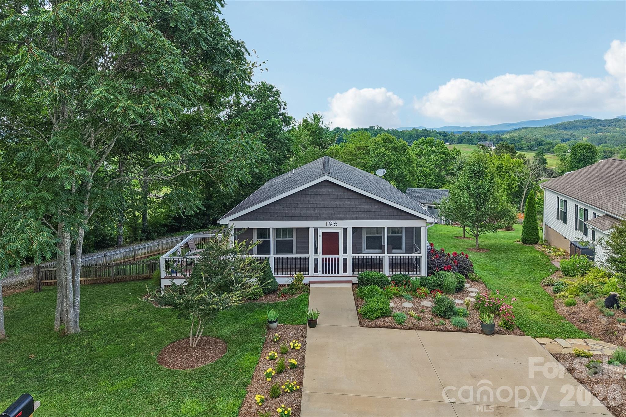 Escape to the beauty of the Blue Ridge Mountains at 196 Tipton Hill Road, where breathtaking long-range mountain views, exceptional care, and peaceful country living create the perfect mountain retreat. Beautifully situated on a meticulously landscaped homesite with no HOA, this move-in-ready home offers approximately 1,333 square feet of thoughtfully designed living space featuring three bedrooms and two full baths, blending comfort, functionality, and timeless charm. Whether you're searching for a primary residence, a second home, or an investment property, this home offers the flexibility buyers are looking for, with short-term rental potential subject to county regulations.
From the moment you arrive, you'll appreciate the outstanding curb appeal created by mature landscaping, colorful seasonal plantings, and the evident pride of ownership throughout. The inviting screened front porch is the perfect place to unwind at the end of the day while enjoying spectacular sunsets that paint the western sky in brilliant colors. Inside, natural light fills the home, creating a warm and welcoming atmosphere that reflects the care this property has received over the years. Designed to embrace outdoor living, the home offers multiple spaces to relax, entertain, and take in the spectacular scenery. A spacious side deck overlooks the fully fenced side yard, providing a wonderful space for pets, gardening, or simply enjoying the outdoors in privacy. The expansive rear deck is truly the centerpiece of the property, showcasing breathtaking layered, long-range views of the Blue Ridge Mountains that provide an ever-changing backdrop throughout every season. Start your mornings with unforgettable sunrises rising over the mountains, and in the evenings, enjoy mesmerizing moonrises that illuminate the landscape, creating a peaceful setting unlike any other. Whether hosting family and friends, enjoying dinner outdoors, or simply soaking in the panoramic scenery, this remarkable space is one you'll never want to leave. Adding even more versatility is the detached workshop, ideal for woodworking, hobbies, crafts, storage, or a home-based business. Just beyond, an additional deck nestled beside the workshop offers another peaceful destination to relax while overlooking the beautifully landscaped yard and taking in the same incredible mountain views. Every outdoor space has been thoughtfully designed to maximize both beauty and functionality, creating your own private mountain sanctuary. One of the property's most unique lifestyle features is its location along picturesque Tipton Hill Road, a favorite among walkers, cyclists, runners, and outdoor enthusiasts. Step outside your front door and enjoy leisurely walks or bike rides along this scenic mountain road, where breathtaking 360-degree mountain vistas unfold around nearly every bend. The quiet surroundings, fresh mountain air, and stunning scenery make this one of Western North Carolina's hidden gems for those who appreciate an active outdoor lifestyle and the beauty of the Blue Ridge Mountains. Despite its peaceful mountain setting, the home is conveniently located within an easy drive of downtown Asheville, downtown Weaverville, shopping, dining, breweries, healthcare, the Blue Ridge Parkway, and countless hiking trails, waterfalls, and outdoor adventures. Offering no HOA, short-term rental potential, beautiful landscaping, multiple outdoor living areas, a screened front porch, side deck, expansive rear deck, fenced yard, detached workshop, and unforgettable Blue Ridge Mountain views, this exceptional property captures everything buyers dream of when searching for a Western North Carolina mountain home. Opportunities like this are rare—where meticulous care, extraordinary scenery, investment potential, and the freedom to enjoy mountain living come together in one remarkable property.