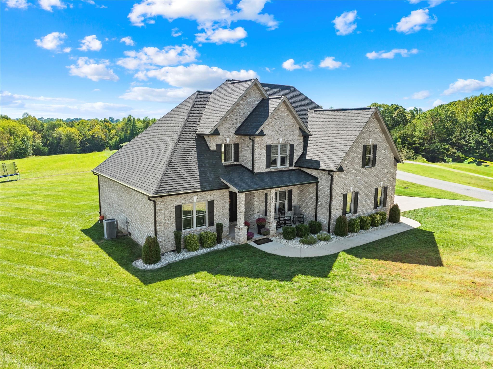 Don't just drive by and wonder... NOW is the time to come check out this next to new, custom-built full brick home offers 5 bedrooms, 3 full baths and timeless elegance throughout! If quality is what you are looking for, search no further! Step inside to find soaring ceilings, a grand foyer, and a striking floor-to-ceiling brick fireplace in the great room. The open-concept design flows seamlessly into the gourmet kitchen featuring custom cabinetry, stainless steel appliances, and a large center island perfect for gathering and entertaining. The main level showcases 9’ ceilings, gleaming hardwood floors throughout, and a luxurious primary suite with a spa-like ensuite highlighted by a gorgeous tile shower and soaking tub. A guest bedroom and full bath are located on the main level along with a formal dining room and laundry room. Upstairs, you’ll find 8’ ceilings, 3 additional bedrooms, and a full bath ideal for guests, office space, or a playroom. Thoughtful details include tinted privacy windows for energy efficiency and curb appeal that shines with a classic rocking chair front porch flanked by stately brick columns. Enjoy outdoor living on the spacious covered rear porch, complete with a built-in gas line for grilling. With nearly an acre of land, there’s ample room to design your dream backyard with plenty of space for a custom in-ground pool! Why wait to build when this home combines luxury, comfort, and endless potential all in one remarkable package! Enjoy the golf cart lifestyle cruising the neighborhood  or downtown Maiden for all the local festivals and parades! Just minutes from Denver, Hickory, Lincolnton, Maiden & Newton, an easy drive to Charlotte via Hwy 16, this location screams COUNTRY LIVING without giving up the convenience of nearby shopping, restaurants and hospitals. *PLEASE NOTE...The outdoor photos do reflect VIRTUALLY STAGED OPTIONS for landscaping and pool! Be sure to check out the video tour!