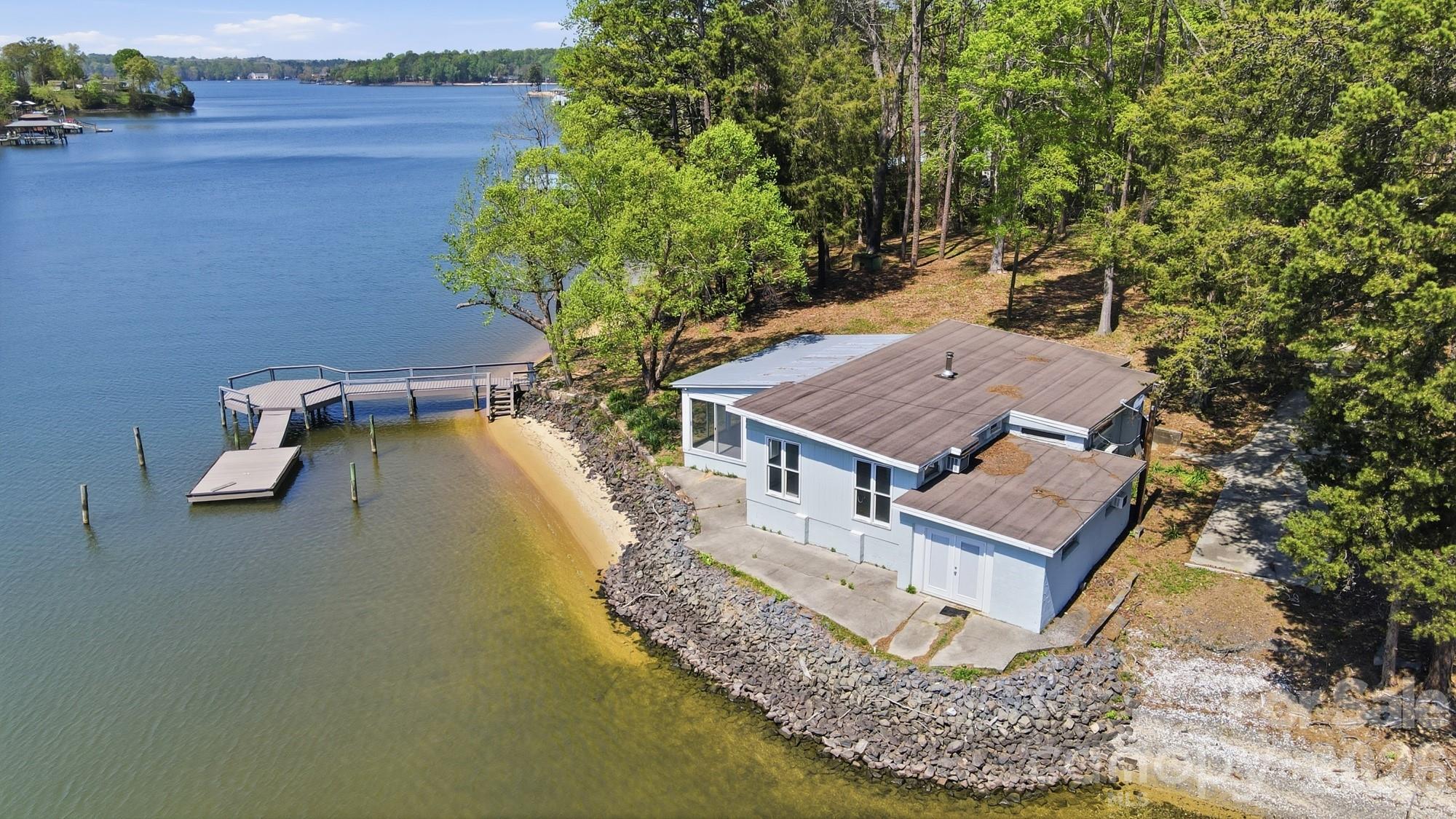 PREMIER WATERFRONT BUILDING OPPORTUNITY on the Mecklenburg side of Lake Wylie! Situated on an approximately 0.74 acre lot with expansive water views and direct access to the main channel, this property offers an exceptional canvas for new construction in a highly sought-after location.  The existing 2-bedroom, 1-bath home is in poor condition and is being sold as-is, making this an ideal tear-down for builders or buyers looking to design and build a custom waterfront residence. The lot’s gentle topography and wide water frontage provide outstanding potential for maximizing views and outdoor living space.  Property includes an older boat ramp in need of repair, offering the opportunity to re-imagine and enhance water access to suit your vision. Surrounded by a mix of renovated and newly constructed homes, this property is perfectly positioned for redevelopment and long-term value.  Rare chance to secure a prime waterfront lot on Lake Wylie.  Bring your builder and create your dream home!  Recent survey available by request.