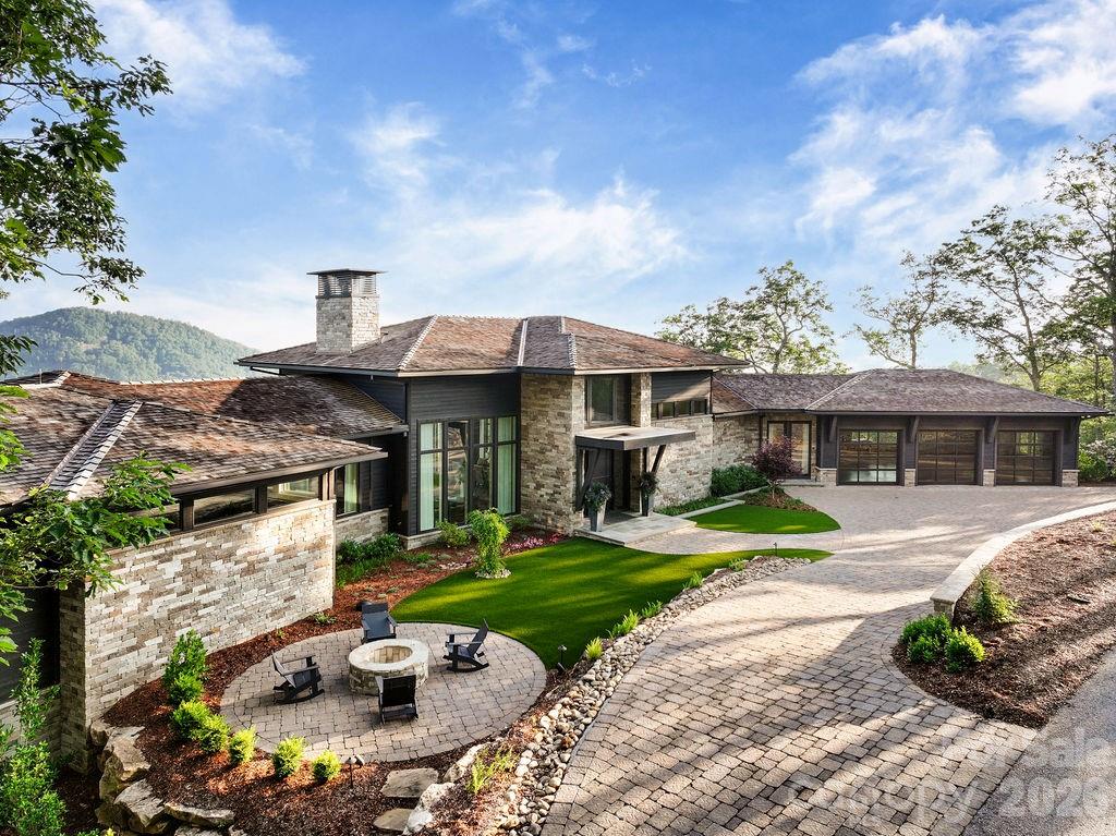 Soaring above the Blue Ridge Mountains in The Cliffs at Walnut Cove,  Asheville’s only private gated golf community, 510 Cloud Top Way delivers year-round, long-range mountain views from virtually every room in the house. Completed in 2023 and crafted by Dillard-Jones Builders, a Preferred Builder with The Cliffs and interiors by Tribus Interior Design, this 7,400+ square-foot residence on 1.07 manicured acres is as technically sophisticated as it is visually striking. The stacked stone and cedar exterior, cedar-shake roof, and blue flagstone entry set a tone of grounded, intentional luxury — then the steel entry door opens, and the scale of the two-story great room, exposed steel beams, and a wall of expansive mountain views take over. The main level is designed for the way people actually live. A kitchen outfitted with Wolf and Sub-Zero appliances anchors the open floor plan, featuring an 11' x 5' island, solid quartz backsplash, and a concealed pantry stocked with a second Sub-Zero refrigerator and wine cooler. The dining and great room flow seamlessly to a fully outfitted outdoor deck with a built-in Sedona gas grill, retractable phantom screens, and IPE decking — an extension of the home living space, with protected views of Pisgah National Forest and sweeping sightlines to downtown Asheville and the Biltmore Estate. Two dedicated home offices — one with custom-soundproofed walls — meet the demands of modern professional life without sacrificing the view. The primary suite is a masterclass in quiet luxury: coffered ceilings, French doors to the private deck, and a custom floating king bed. The  spa bathroom continues the standard with radiant heated marble floors, a zero-entry steam shower with treetop views, a Bain Ultra soaking tub, and a marble wardrobe island anchoring the expansive primary closet. The lower level fully expands the home's personality. A beamed media room with a MadVR Envy video processor and wall screen anchors the space, with a bar kitchenette with a Marvel keg refrigerator, waterfall quartz island, and glass-front Sub-Zero, and a temperature-controlled glass wine cellar steps away. On one end, a dedicated gym with epoxy concrete floors and separate HVAC, and a guest suite with en suite bath. On the other end, another primary guest suite with en suite bath, a bunk suite sleeping four, and an additional guest suite — space for family, guests, or full-time multigenerational living, all with the same long-range views. Infrastructure is equally uncompromising: a 48KW Kohler whole-house generator, Savant smart lighting and sound, three-zone Lennox HVAC, three Navien on-demand water systems, FloLogic leak detection, Ultravation air filtration, EV charger, home elevator, and a Savant-integrated exterior sound system including a firepit with hidden speakers. Where the mountains meet masterful design, 510 Cloud Top Way stands in a category of its own. A club membership at The Cliffs is available for purchase with this property giving you access to all seven communities.