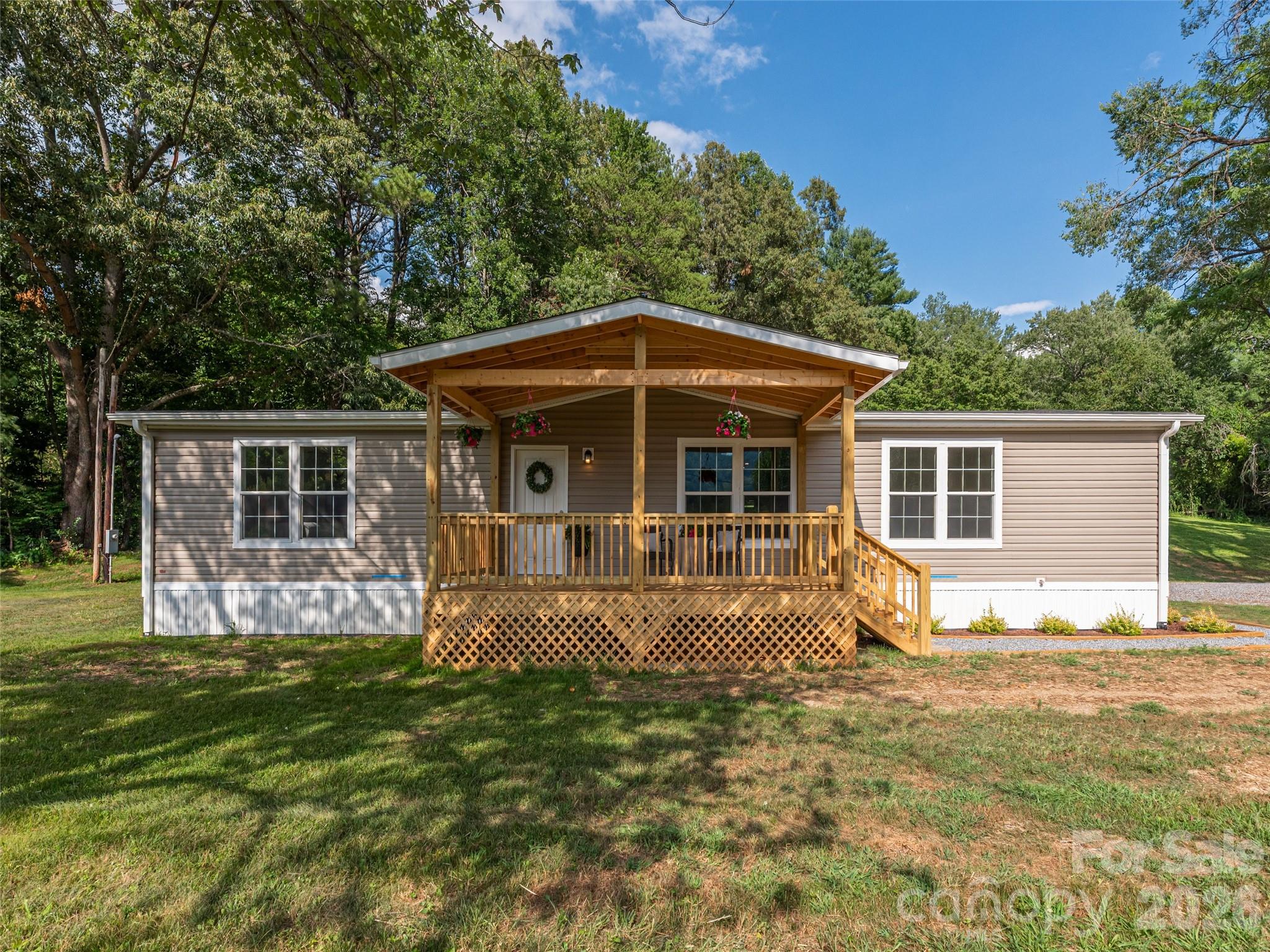 Beautifully crafted, like-new custom double-wide with premium upgrades and mountain views, just moments from Western Carolina University. This completely custom home is ideal for anyone working or studying at the University. It includes a fully transferable factory warranty and features numerous upgrades, including 2x6 flooring, 2x4 sheetrock walls, crown molding, custom cabinetry, and brand-new stainless steel appliances. The 10x20 covered front porch is perfect for morning coffee or evening grilling while enjoying the mountain views. An attached 28x60 rear carport offers parking for up to four vehicles, along with additional covered space. The property also includes a 10x16 storage building/workshop for added functionality. Situated on just under an acre with no restrictions, there is ample room for gardening, farm animals, recreation, and outdoor living—an excellent opportunity in a desirable location.