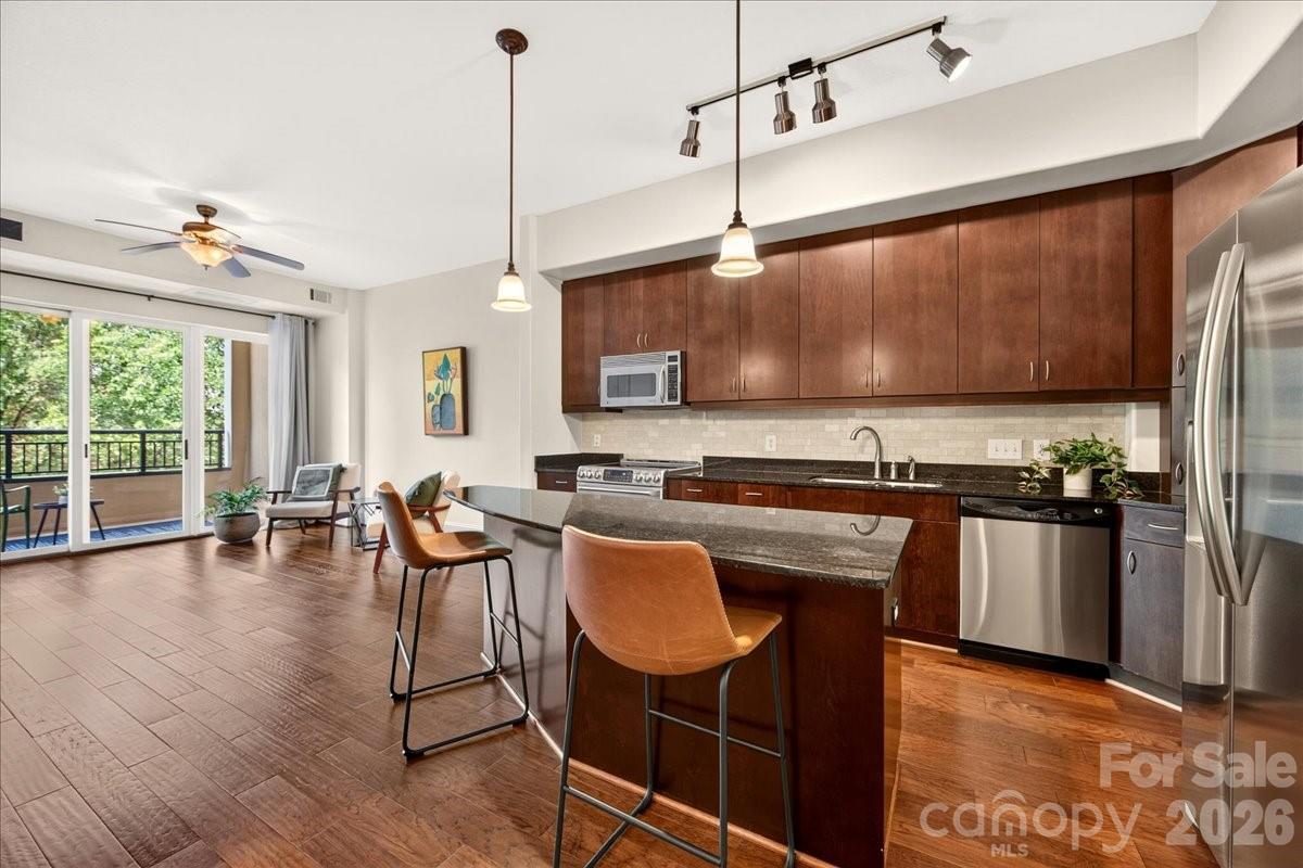This pristine Piedmont Row 1-bedroom + office condo is truly turnkey and offers low maintenance, easy living! The high ceilings, open concept main living area, and covered balcony overlooking foliage create an airy and comfortable space, while the versatile flex room is tucked away for a perfect office or den. The kitchen offers lots of cabinet storage, a large island with room for counter seating, stainless steel appliances, granite countertops, a tile backsplash, and an adjacent dining area. Upgraded features include engineered hardwood floors, a custom walk-in closet, and living room ceiling fan. A new HVAC system installed fall 2025 and a radon mitigation device installed 12/2021 offer peace of mind. Refrigerator, washer, dryer convey. 1 assigned parking space in the secure parking deck. Piedmont Row offers ultra-convenient access to the SouthPark Loop, the Greenway, dining, coffee, grocery, shopping, spas, fitness, plus close proximity to Uptown. Welcome home!