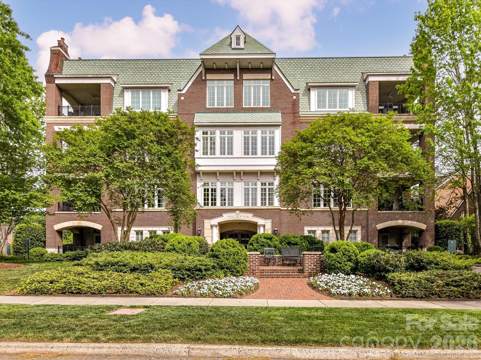 Experience luxury living in Myers Park with this beautifully appointed 3 bed/3.5 bath condo at The Croydon. Gracious foyer opens to spacious living room with coffered ceilings and separate formal dining room with tray ceiling, all with wood-flooring. The living room has a fireplace, a wall of windows allowing lots of light and lovely french doors leading to a covered porch with gas grill. The original kitchen plan was enlarged and features distressed ceiling beams, a cozy breakfast area overlooking the mature trees, upgraded cabinetry with granite counters, built-in work station and a built-in bar with sink, ice maker and a brand new wine cooler. There are also brand new full-sized separate refrigerator and freezer, built-in microwave, trash compactor, pantry cabinets, and Thermador gas cooktop. The large center island has a butcher-block countertop, warming drawer and great storage. The primary suite has french doors to a private porch, built-in drawers/cabinets/bookcases and 5 closets, one of which is a large walk-in. Primary bath has soaking tub, over-sized glass shower and water closet with bidet. There are two additional guest suites, each with ensuite baths and walk-in closets, and one has access to the covered porch. Full laundry room with sink, wall cabinets, built-in ironing board and separate storage closet. Powder bath off foyer. Two assigned parking spaces and assigned storage closet in garage with 3 walls of shelving units. 
Lots of storage throughout! Ample guest parking on adjacent side-street and walkable neighborhood within a short distance to great dining and shopping.