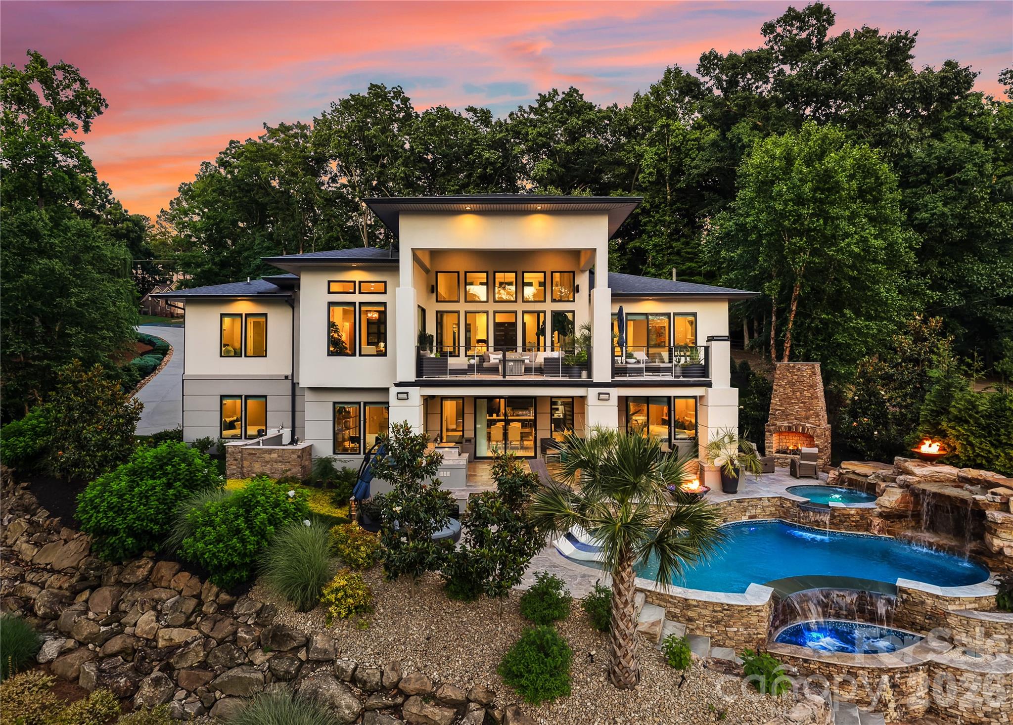 A masterpiece of modern waterfront architecture, Casa Luce is a rare offering on the shores of Lake Norman where award-winning design, extraordinary craftsmanship, and an unparalleled lifestyle converge. Privately positioned on approximately 1.2 acres with over 220 feet of pristine shoreline, the residence enjoys a coveted eastern orientation across the water, welcoming the morning sun and long prized in many traditions as a symbol of prosperity, renewal, and positive energy. This modern architectural showpiece captures breathtaking sunset views, exceptional natural light, and a level of privacy seldom found on the lake.

Recognized as the 2019 Best Build on Lake Norman and crafted by renowned Titan Builders, the residence was designed to blur the boundaries between indoor and outdoor living. Dramatic walls of Anderson glass frame panoramic water views from nearly every room, while soaring ceilings, reclaimed white oak flooring, and custom steel, glass, and wood details create a sophisticated yet welcoming atmosphere. 

Offering over 4,700 square feet, the thoughtfully designed floor plan features five bedrooms and five full bathrooms, including a stunning main-level owner's retreat with private terrace access overlooking the water. The heart of the home is centered around a chef's kitchen appointed with premium Wolf and Sub-Zero appliances, custom cabinetry, an oversized quartz island, apron-front sink, and a newly redesigned walk-in pantry complete with custom built-ins and a dedicated wine refrigerator. 

A striking floor-to-ceiling fireplace feature wall anchors the main living space, while a custom floating staircase serves as a work of art connecting both levels. Designed for effortless entertaining, the walkout lower level offers exceptional flexibility with a second full kitchen, spacious gathering areas, guest accommodations, and a custom wine room. Every detail has been curated to elevate both everyday living and grand-scale entertaining. 

The outdoor experience is equally remarkable. Extensive new travertine terraces surround a newly added resort-inspired pool overlooking the lake. A custom outdoor kitchen, newly constructed gas stone fireplace, professional landscaping, and multiple waterfront entertaining spaces create an environment designed for unforgettable gatherings. The newly added private dock provides immediate access to Lake Norman's coveted boating lifestyle, while the rock seawall and expansive shoreline further enhance the property's long-term value and enjoyment. 

Beyond its beauty, Casa Luce offers exceptional peace of mind with a whole-house generator, dedicated propane system, spray foam insulation, security system with cameras, upgraded septic system, reverse osmosis water filtration, well filtration system, meticulously maintained HVAC systems, and a three-car garage.

Without the restrictions of an HOA and located just minutes from premier golf, marinas, waterfront dining, boutique shopping, and everyday conveniences, Casa Luce represents a rare opportunity to own one of Lake Norman's most celebrated modern waterfront residences.

Casa Luce is an extraordinary expression of architecture, craftsmanship, and lakefront living.