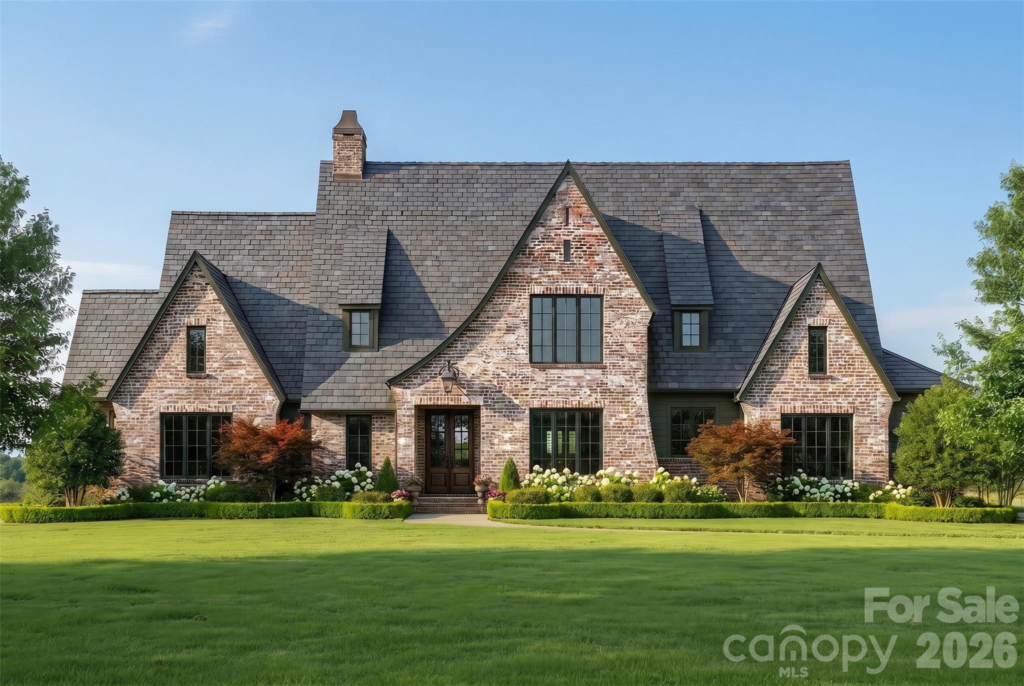 Nestled on a sprawling 2.4-acre estate lot in one of Davidson's most coveted new communities, this stunning Kristi plan by Frusterio Designs represents the pinnacle of custom home living. To be built by Davidson's premier luxury builder — this Country French, European, and Tudor-inspired masterpiece offers 4,273 square feet of thoughtfully designed living space across two beautifully appointed levels.
From the moment you arrive, the home's striking brick and stone exterior commands attention, with sweeping rooflines, architectural dormers, and lush, manicured grounds that set the tone for the elegance within. Step through the covered entry porch into a grand foyer that flows effortlessly into the heart of the home — a soaring great room spanning over 20 by 19 feet, perfectly suited for entertaining or quiet evenings in.
The gourmet kitchen is a chef's dream at 14 by 22 feet, anchored by a generous pantry, drop zone, and an adjoining family dining room that keeps the whole family connected. A wet bar adds a refined touch just steps away. The main-level primary suite is a true retreat — a spacious 15 by 19-foot sanctuary complete with a spa-inspired master bath and dual walk-in closets. A second bedroom on the main floor offers flexibility for guests or multigenerational living, alongside a dedicated office and a convenient powder room.
Upstairs, a loft provides the perfect bonus space, joined by two additional bedrooms — including an optional office/bedroom — each with private bath access and ample attic storage. Five bedrooms, five full baths, and a three-car side-entry garage round out this exceptional floor plan.
Step outside to the screened covered porch — a remarkable 30 by 18-foot outdoor living space complete with an outdoor grill station — where you'll savor peaceful evenings overlooking your private estate acreage.
And here's what makes the homes truly special.  With estate-sized lots like this, the possibilities are limitless. Need a fourth garage bay? Done. Dreaming of a resort-style pool? Absolutely. Want to add a pickleball court, a guest cottage, or a custom workshop? Holliday Homes has the expertise and the land to make it happen. Every home in this community is fully customizable — floor plans, finishes, and features tailored precisely to the way you live.
Beyond the property itself, the location is second to none. A short drive puts you in the heart of downtown Davidson, where acclaimed restaurants, boutique shops, and a vibrant small-town culture await. And just steps away, the highly anticipated Summit Farms community promises an extraordinary neighborhood experience that only elevates the lifestyle here.  Final pricing subject to final plans and specifications.