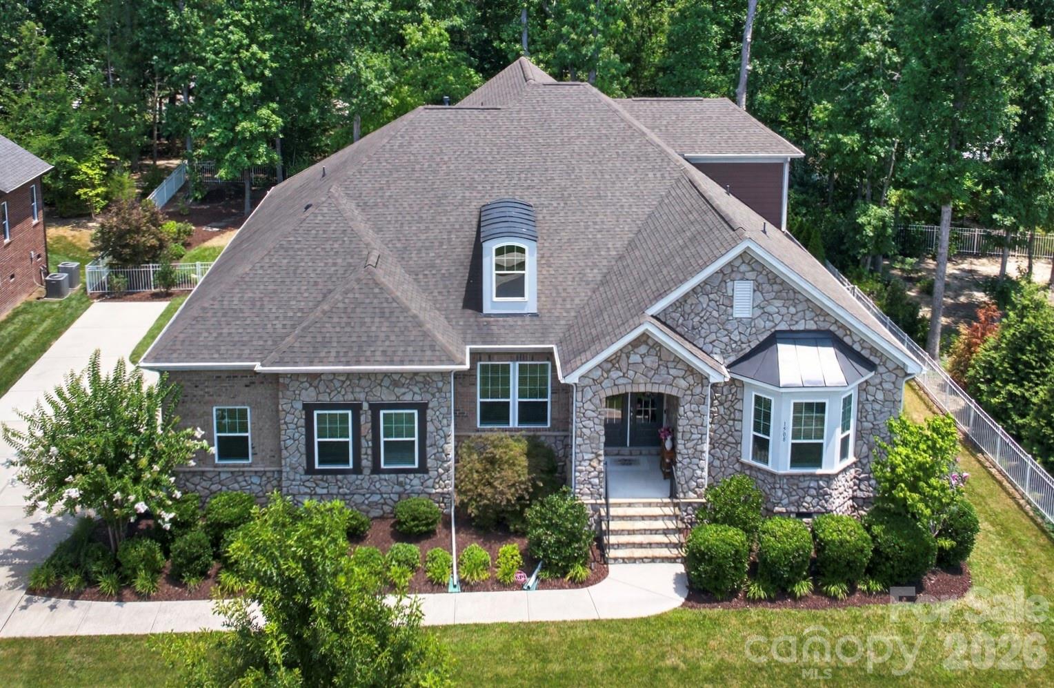 Exceptional full brick 4 bedroom/3.5 bath home with 3 car garage in Waxhaw's sought after Lawson community! This Mattamy Homes build is from their Signature Collection.  Original homeowners have spared no expense in making this home a true masterpiece.  An entertainers dream- the outdoor living spaces are a true extension of the home. The sunroom is a showstopper and features EZE Breeze windows, a wood burning fireplace and infrared heaters. Another separate patio area off sunroom features a sunken hot tub. The covered outdoor kitchen features flagstone floors, leathered granite countertops with/ chiseled edge, natural gas grill w/ separate burners, sink, and fridge. The additional flagstone patio includes a curved seating wall and water feature with 12 volt lighting- all in a fully fenced and professionally landscaped backyard. As you enter the home the craftmanship is apparent as soon as you walk through the double front doors. The interior features hardwood floors on main, heavy millwork, upgraded designer lighting and fans, and a neutral paint palette, creating an elevated space that is completely move-in ready.  The Westcott Estate floorplan has a grand 2 story foyer as you enter that opens into  the elegant dining room with coffered ceiling. Nearby a private hallway leads you to secondary bedrooms that share a Jack-and-Jill bathroom.  Beyond the foyer is a large great room with a double sided fireplace.  The gourmet kitchen and breakfast area features a large island, breakfast bar, granite countertops, tile backsplash, stainless steel appliances, walk in pantry and Butlers pantry with wet bar and beverage refrigerator.  Main level laundry room with custom cabinets and a utility sink is both functional and beautiful.  The 3 car side load garage has epoxy floors and custom cabinets. Homeowners extended the driveway as well for additional parking! The Primary Suite is tucked away on main level separate from the secondary bedrooms.  Two closets and a spa-like en-suite bathroom with a soaking tub, separate stall shower, water closet and dual vanities make this a true retreat. Upstairs a professionally installed, temperature controlled wine room is adjacent to the large loft with custom cabinets and granite countertops. An additional bedroom with hardwood flooring and full bathroom upstairs offer even more options.  Luxury vinyl plank flooring on second floor in loft and hallway. Lawson residents enjoy resort style amenities including a clubhouse, multiple pools, waterslides, fitness centers, tennis and pickleball courts, playgrounds, walking trails and more!