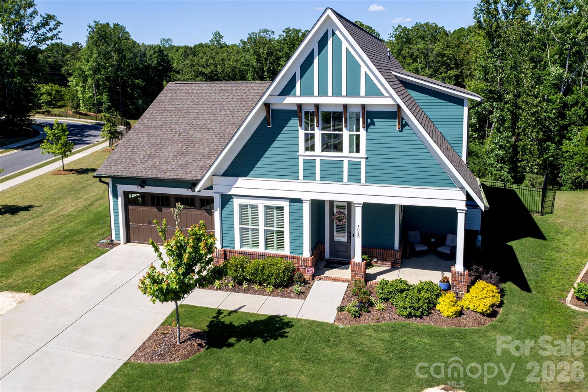 Rare opportunity to own a home in Cottages at Marvin Gardens, an intimate 25-home 55+ active adult community tucked beside Marvin Gardens and ideally located near the Union and Mecklenburg County line. Lawn care and common area maintenance are included, making it easy to enjoy a low-maintenance lifestyle without sacrificing space or comfort. Designed for both everyday living and entertaining, this 4-bedroom, 3-bath home offers a flexible floorplan with two bedrooms on the main level and two upstairs. The open-concept layout features 10-foot ceilings, abundant natural light, SPC plank flooring throughout much of the main level, and plantation shutters on many windows. The kitchen is the heart of the home, featuring quartz countertops, gas cooking, a tiled backsplash, ceiling-height cabinetry, a large island, and an oversized butler's pantry with additional cabinetry and workspace. The adjoining family room is anchored by a gas fireplace with wood mantel, built-ins, window seats, and large picture windows overlooking trees and common area. The main-level primary suite offers a peaceful retreat with wooded views, a custom walk-in closet, and an en suite bath featuring dual vanities, linen storage, and an oversized tiled shower with frameless glass enclosure and built-in seat. A spacious laundry room with tile flooring, granite counters, cabinetry, and a utility sink adds everyday convenience. Hardwood stairs lead to a large loft, two additional bedrooms with walk-in closets, and a shared Jack-and-Jill bath with a deep soaking tub, tile surround, and additional linen storage. Two attic spaces, including a walk-in attic, provide storage rarely found in homes of this style. Outdoor living is equally impressive with a welcoming wraparound front porch, screened rear porch, expansive paver terrace with gas firepit, fully fenced backyard, and irrigation system. Adding to the sense of privacy and space, the property borders common area at the front, side, and rear. Just a short sidewalk stroll to Publix, restaurants, and everyday conveniences, this home combines spacious, thoughtfully upgraded interiors with the easy lifestyle of one of the area's most desirable active adult communities.