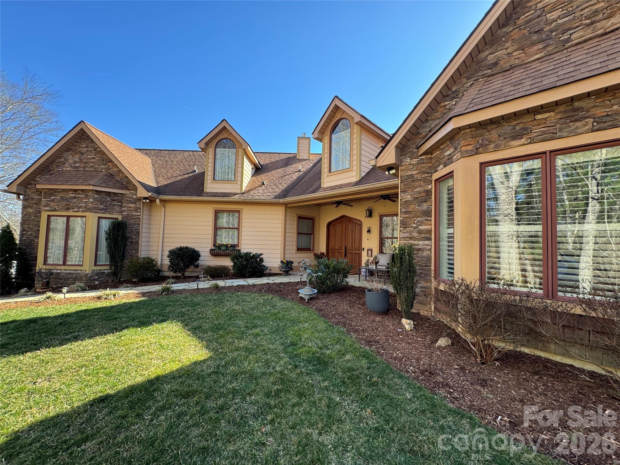Prepare to be impressed as you traverse the long private driveway to this exceptional one-level retreat, perfectly positioned on the 13th fairway in the highly desirable High Vista gated community with multiple amenities. Offering the utmost in privacy and a picturesque natural setting, this stunning three-bedroom, 2.5-bath home seamlessly blends elegance, comfort and mountain living. A charming flagstone walkway leads to the inviting covered front patio, setting the tone for what awaits inside. Step through the striking solid wood Biltmore French doors into a warm and welcoming great room, where high ceilings, 8-foot doors and an open floor plan create a sense of space and flow throughout. The great room is anchored by an impressive floor-to-ceiling river stone fireplace with a rich cherry wood mantle, complemented by built-in bookcases and a dedicated media area. Designed for both everyday living and entertaining, the great room opens effortlessly into the dining area and a beautifully appointed kitchen. Here, you’ll find an abundance of cabinetry, granite countertops, stainless steel appliances including a gas cooktop, wall oven, and microwave, a striking copper exhaust hood and a tile backsplash with decorative inlays—offering both function and style. The primary suite is a true private retreat, featuring a tray ceiling, plantation shutters, walk-in closet, and a cozy fireplace. The luxurious en-suite bath boasts heated tile floors, dual granite vanities, a dedicated makeup area, stunning vessel sinks, and a zero-step double walk-in shower with multiple body sprays, along with a private water closet. A thoughtfully designed split-bedroom floor plan provides two spacious guest bedrooms and a full bath with granite vanity, copper hammered vessel sink and a tub/shower combination. Completing the main level is a powder bath with pedestal sink and well appointed laundry room with sink and cabinetry. Enjoy year-round relaxation in the sunroom, complete with its own heating and air wall unit and a wall of windows that showcase mountain and golf course views. Step outside to the spacious patio—perfect for entertaining or simply soaking in the serene surroundings. Additional features include a two-car garage and a dedicated golf cart garage. Experience the best of mountain lifestyle living—whether you’re enjoying your morning coffee on the covered front porch, unwinding in the sunroom or entertaining on the patio with sweeping fairway and mountain views. High Vista offers an array of amenities including golf, tennis, pool, clubhouse, and vibrant social activities. Conveniently located near Hendersonville, Asheville, Brevard, and the airport, this home presents a rare opportunity to own a truly special property in one of the area’s most sought-after communities.