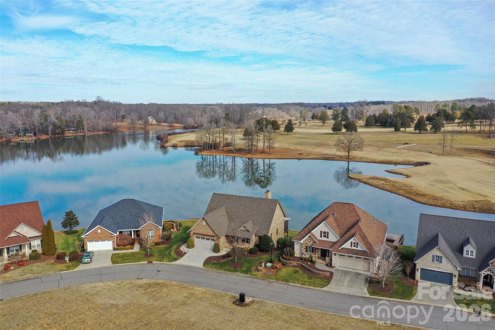 Lake Front and Golf course living at The Reserve, an exclusive boutique community where golf course greens meet shimmering waters. Conveniently located to Hwy 64, I-40 and Hwy 801,  This one-of-a-kind retreat offers a serene escape from the everyday. Inside, soaring beamed ceilings and a majestic stone fireplace anchor a great rm framed by walls of windows, open to the kitchen and dining area, flowing seamlessly to a screened porch AND open-air deck, perfect for entertaining. The main level features a sophisticated wood-paneled office, primary en suite w/heated floors, laundry and a built-in drop zone. The beauty intensifies on the lower level, where panoramic views serve as the backdrop for a versatile recreation hub or second living suite. Two additional en suites, with access to covered patios, luxurious lawn, pier and lake. Enjoy peace of mind with a NEW roof (2023/24) and updated heat pumps (2019). You will LOVE the storage in the unfinished area with moisture-resistant poured concrete walls. Additional lot available for purchase, with purchase of home.