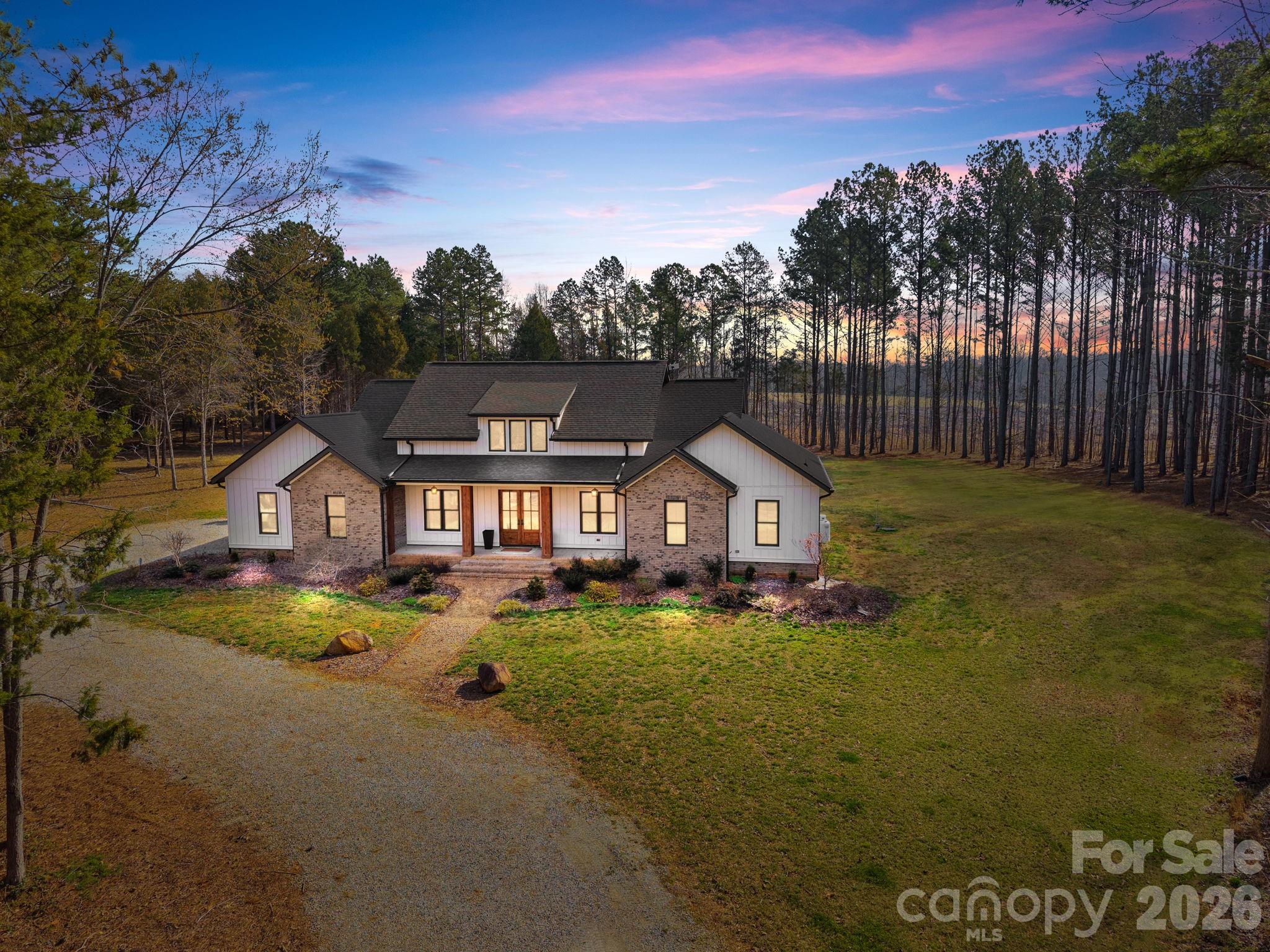 Welcome to 465 Baxx Drive, where breathtaking privacy and exceptional craftsmanship come together on 14.21 acres of tranquil countryside. From the moment you arrive, the inviting rocking chair covered front porch sets the tone for the remarkable home that awaits inside. Step through the grand double doors into an open, airy floorplan. Soaring 10-foot ceilings and 8-foot custom doors create a sense of elegance throughout. The stunning living room is the heart of the home, featuring a floor-to-ceiling stone fireplace, custom built-ins, and a stylish bar area. The open dining area flows seamlessly into the chef’s gourmet kitchen, a true showpiece boasting custom cabinetry, soft-close drawers and cabinets, quartz countertops, tile backsplash, and an oversized center island. High-end stainless steel Kutch appliances, including the refrigerator, and a spacious walk-in pantry. Convenience meets thoughtful design with a main-level laundry room complete with abundant cabinetry and generous quartz counter space. The luxurious primary suite is a private retreat featuring a large walk-in closet, double vanity, soaking tub, and an expansive walk-in tile shower. On the opposite side of the home presents two generously sized bedrooms that share a well appointed bathroom. Upstairs, you’ll find a versatile bonus room and full bathroom, perfect for a guest suite, home office, or recreation space. Step outside and experience the true beauty of this property. The covered back porch with pine tongue-and-groove ceilings provides the perfect place to relax and take in the peaceful surroundings. With 14.21 acres of private land, there is endless opportunity for exploring nature, gardening, or simply enjoying the serenity of your own personal retreat. Impeccable finishes, stunning design, and unmatched privacy make this one-of-a-kind property a place you’ll want to call HOME!