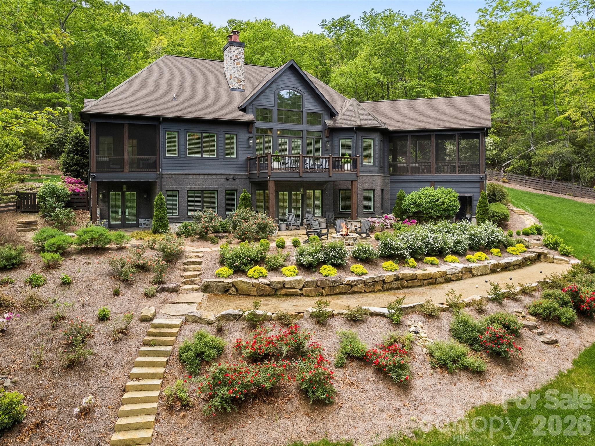 Nestled within the gates of The Cliffs at Walnut Cove, 1455 Flint Rock Trail offers an exceptional mountain lifestyle. This masterfully crafted retreat greets you with an exquisite stone facade, sophisticated dark accents, and a striking arched entryway. Inside, the foyer reveals a towering vaulted ceiling and an elegant open staircase, perfectly balancing grand, light-filled entertaining spaces with quiet, refined private areas.

The main floor features a soaring living room anchored by a magnificent floor-to-ceiling dry-stack stone fireplace and an expansive wall of windows framing the forest canopy. Culinary enthusiasts will delight in the custom kitchen, detailed with floor-to-ceiling textured tile, deep blue cabinetry, premium appliances, and a central island. Nearby, an enclosed screened porch features a vaulted wood-beamed ceiling and a cozy stone fireplace for year-round enjoyment. The main level also hosts a sophisticated primary suite with dual walk-in closets and a spa-like bath with a freestanding soaking tub. An integrated elevator provides effortless access to the lower level, which offers a large family room opening to the outdoors, alongside three additional bedrooms, two featuring private en-suite baths.

Bordering the serene expanse of the Pisgah National Forest, the property’s private outdoor oasis includes multiple decks, terraced gardens, a fenced backyard, and a dedicated stone fire pit. Living here offers a rare combination of high-altitude privacy and convenient access to the Blue Ridge Parkway and Asheville. An available membership unlocks an unparalleled lifestyle, pairing the championship Jack Nicklaus Signature golf course, award-winning clubhouse, and fine dining at 'The Tavern' with a state-of-the-art 18,000-square-foot wellness center, pools, tennis, and a serene spa. This estate represents the perfect blend of mountain serenity and premier amenities, where a single membership opens a world of adventure across seven private communities.