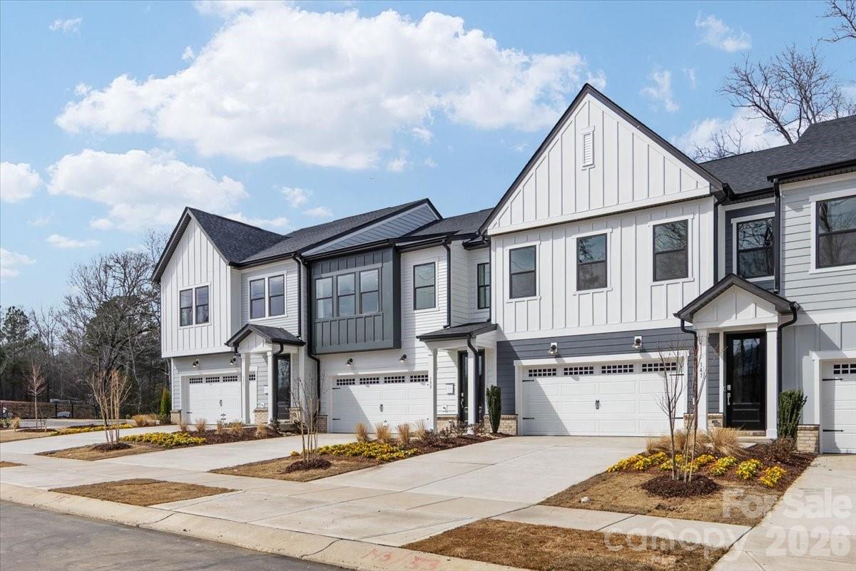 Welcome to 143 Landy St, where thoughtful design meets low-maintenance living at Camryn at Southbridge in Fort Mill. This 3-bedroom, 2.4-bath Falcon plan offers 2,055 square feet of smart, flexible living space across two stories, complete with a 2-bay front-load garage and driveway. A foyer hallway with tray ceilings opens into an airy first floor anchored by a gourmet kitchen appointed with frost cabinets, white quartz countertops, a large single-bowl stainless steel sink, Delta Essa Touch faucet on the island, GE 36" gas cooktop, and designer Kichler Birkleigh pendant lighting. A convenience cabinet package adds double roll trays, a base waste basket, and select-level upgrades. The dining space flows through an 8-foot-wide, 8-foot-tall sliding glass door to a private outdoor living area backed by tree-line views. A drop zone and half bath sit conveniently near the garage entrance. Oak box stairs with open rail lead to the second floor, where an open rail landing, loft space, laundry room, two secondary bedrooms, and a tiled tub secondary bathroom await. The primary suite features a dual vanity bath with a tiled walk-in shower complete with a built-in seat and direct access to the walk-in closet. Positioned with no direct front or rear neighbors and finished in modern farmhouse architecture with a defined gable roofline, this home offers both privacy and curb appeal within minutes of Kingsley Town Center, Anne Springs Close Greenway, top-rated schools, and premier shopping and dining.