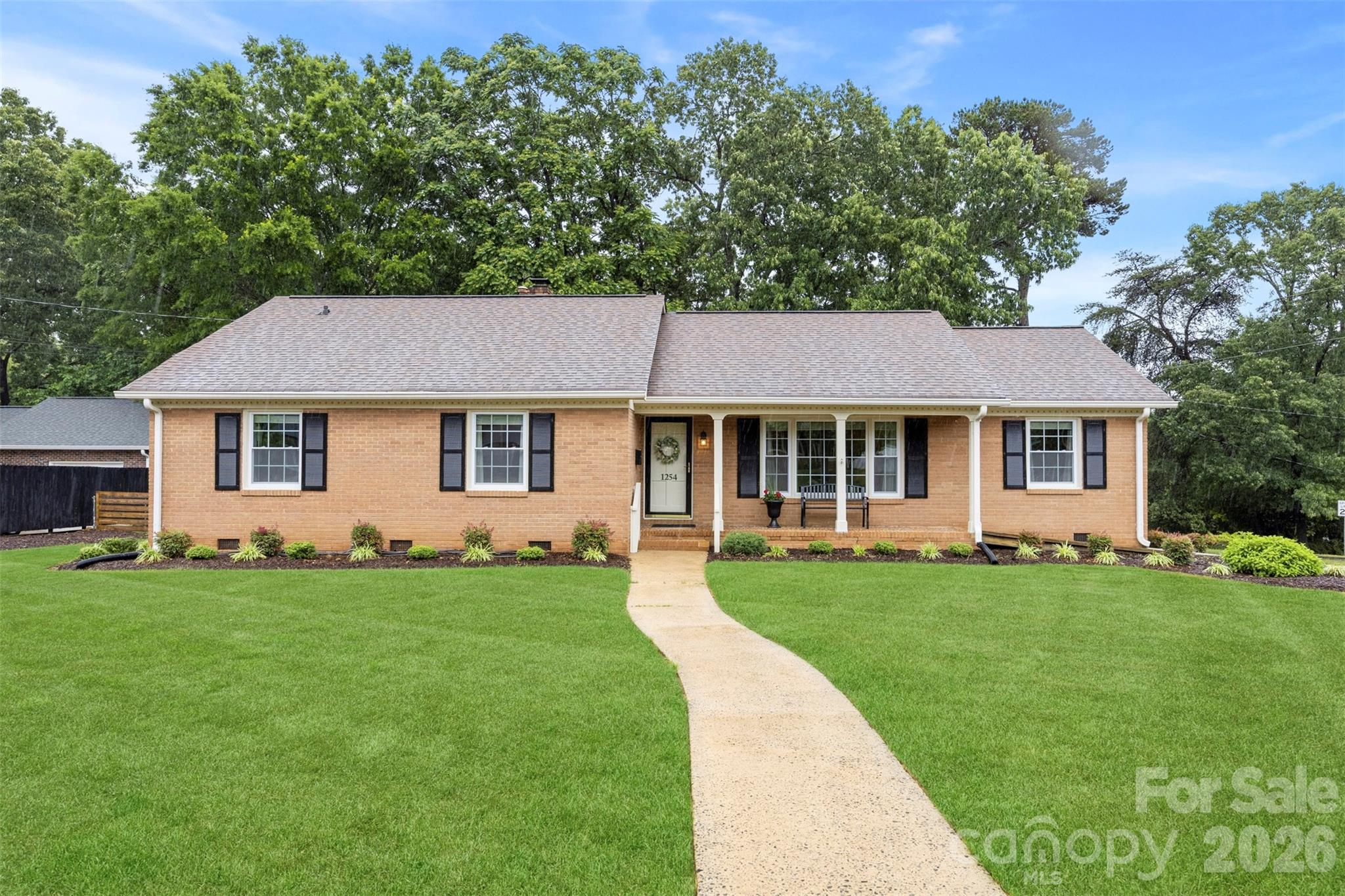 Beautiful full brick ranch situated on a spacious corner lot offering timeless charm and functional living space throughout. Hardwoods run throughout the home. Formal foyer entry opens to a bright living room and dedicated dining area. Kitchen features updated appliances, abundant cabinet/counter space, and breakfast area. Cozy secondary living space with brick fireplace provides additional entertaining or relaxing space. Spacious primary suite includes dual closets. Oversized secondary bedrooms offer generous closet storage. Fenced backyard with patio creates the perfect outdoor setup for entertaining, pets, or play. Convenient single-story living with great curb appeal and mature lot setting. Do not miss this one!