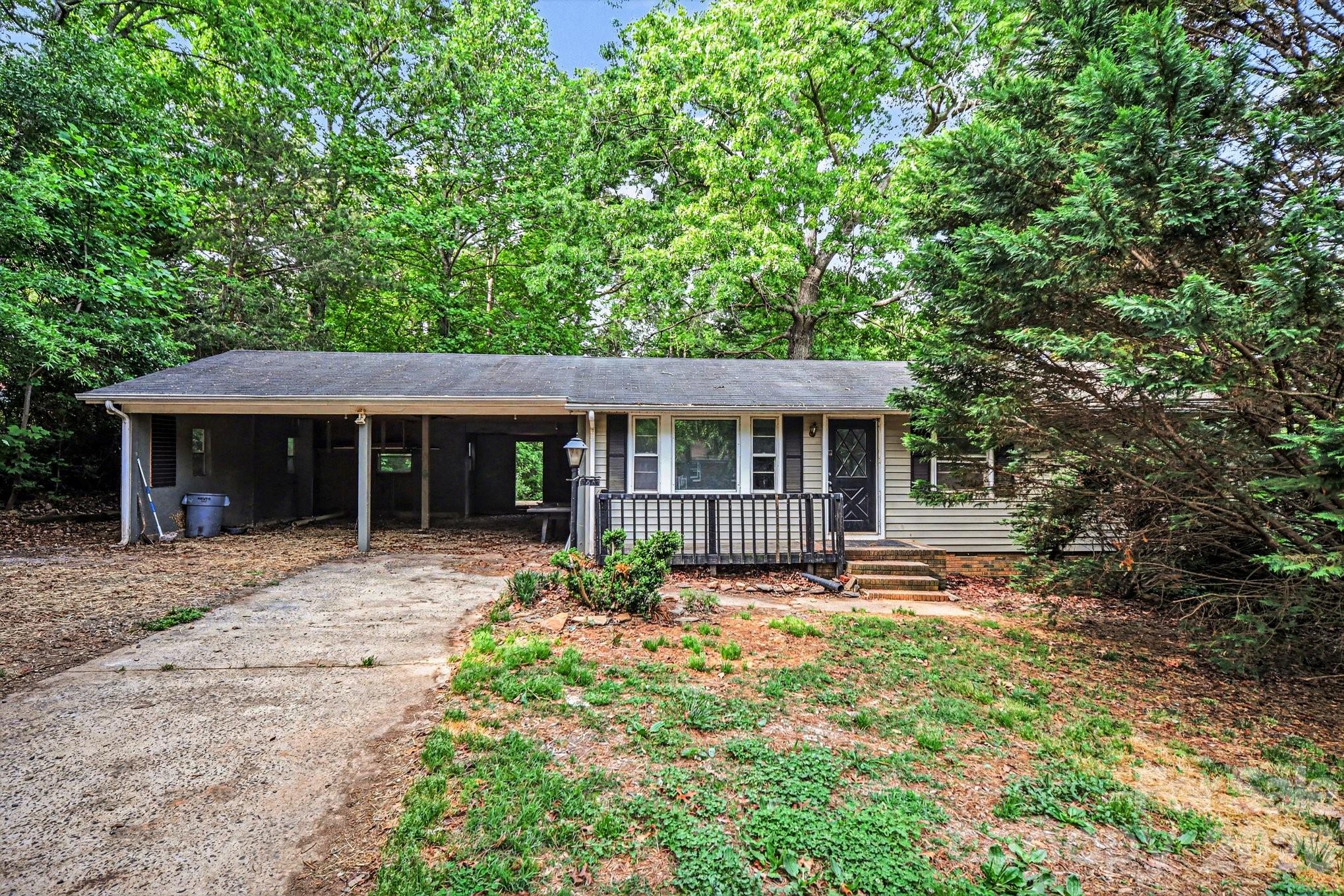 This 3-bedroom, 1-bath ranch offers a fantastic chance for investors, flippers, or buyers looking to renovate and build equity. Nestled on a spacious, wooded lot, this property provides a private, peaceful setting surrounded by mature trees. Inside, the home features a functional single-level layout with a generously sized living room filled with natural light from multiple windows. The kitchen offers ample cabinet storage, room for dining, and a layout that can easily be reimagined into an open, modern space. All three bedrooms are well-sized and include closet space, while the full bathroom is centrally located. The home does need updates and repairs, as reflected in the condition, making it ideal for those looking to customize or invest. Existing flooring, cabinetry, and finishes provide a starting point for renovation. Exterior features include a covered carport, extended driveway, and a screened-in porch perfect for enjoying the wooded surroundings. The backyard offers plenty of space for outdoor living, gardening, or expansion, with a deck area and additional outdoor structures already in place. Conveniently located near local shops, dining, and major roadways, this property combines quiet living with accessibility.