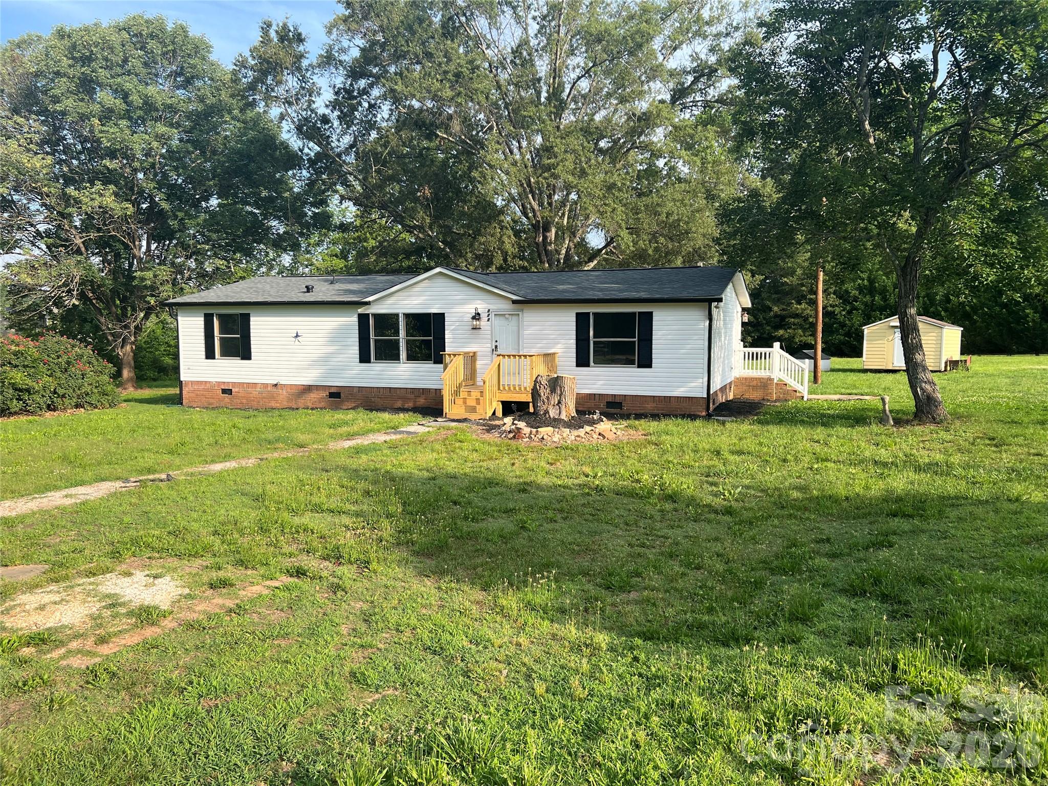 This three bedroom two bath home just received a new roof ,new flooring ,new paint , all new lighting ,granite countertops, new appliances ,and sits on a 1.5 acre lot. As a large oak shade tree ,outside storage building very level lot , lots of privacy close to Clover High school and Griggs Road Elementary. 1/2 mile to each.
Also has new front deck, new rear deck, new gutters, new plastic vapor barrier under home and Brick foundation. It is 100% move-in ready. You can get financing for 30 years. I can help you with that.  The home sits off the road 1000 feet so you never hear traffic going up in town the road. The home has been DE-TITLED!  Even has room for a garden. Agent is the owner. 980-522-6833 Jimmy