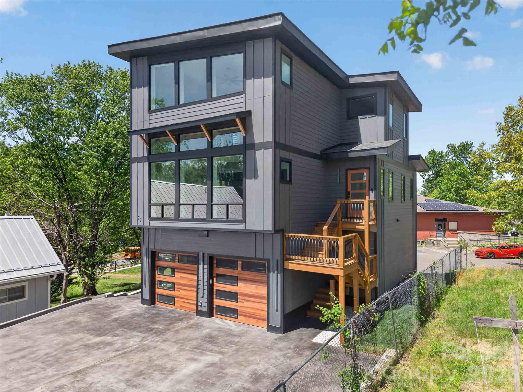 Experience the perfect blend of modern luxury, cutting-edge smart home technology, and exceptional walkability in this newly constructed contemporary residence located in the heart of highly sought-after West Asheville. Positioned just moments from the energy of Haywood Road, this home places you within easy reach of some of Asheville’s most celebrated destinations, including Biscuit Head, Sunny Point Café, Nine Mile, The Admiral, and Plant, along with local favorites like Hole Doughnuts and Odd’s Café. Enjoy nearby breweries such as New Belgium Brewing, Archetype Brewing, and Wedge Brewing, plus quick access to the River Arts District, the French Broad River Greenway, and downtown Asheville just minutes away delivering a lifestyle that is as vibrant as it is convenient.

Thoughtfully designed across three levels, this home offers over 3,400 square feet of refined living space with an emphasis on comfort, efficiency, and elevated everyday living. From the moment you enter, you’re welcomed by an open-concept floor plan filled with natural light, clean architectural lines, and seamless flow between living, dining, and kitchen spaces.

The chef’s kitchen is both striking and highly functional, featuring a large center island with breakfast bar seating, walk-in pantry, wine and beverage refrigerator, and a 5-burner gas range. High-end smart features elevate the experience, including a voice-activated exhaust hood, smart workstation sink, and electronic faucets with precise temperature and flow control, blending innovation with everyday practicality.

Throughout the home, fully integrated smart technology enhances both lifestyle and security. All access doors are equipped with advanced electronic entry systems offering key, code, and fingerprint access. Each room includes Alexa-enabled integration tied into Lutron lighting systems, allowing full control of interior and exterior lighting via app or voice command. The home is also network-ready with built-in connectivity and surround sound capabilities, ideal for both daily living and entertaining.

The home offers four spacious bedrooms and four full bathrooms, each designed with a clean, contemporary aesthetic. All bathrooms feature floor-to-ceiling tile and frameless glass enclosures, creating a spa-like experience throughout. A main-level laundry room adds convenience, while the flexible lower level provides additional living space for guests, recreation, or a private home office.

Efficiency meets performance with dual fuel HVAC systems, zoned climate control, and a tankless water heater, ensuring year-round comfort. The attached two-car garage includes a built-in Tesla charging station, reinforcing the home’s forward-thinking design and energy-conscious appeal.

Combining prime West Asheville walkability, proximity to Haywood Road’s dining and brewery scene, and easy access to the River Arts District and downtown, this home represents a rare opportunity to own a truly next-generation property in one of Asheville’s most dynamic and desirable neighborhoods.