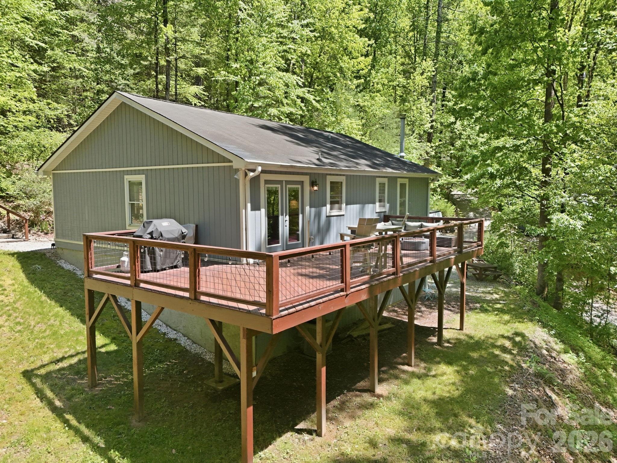 Tucked away in a peaceful mountain setting on 1.12 private acres, this beautifully updated Flat Rock home offers the ideal blend of comfort, character, and usable outdoor space. The drive into the community runs alongside portions of the scenic Hungry River, and residents enjoy private community river access with trout stocked just upstream near the state hatchery.

The main level features an open-concept living area with vaulted ceilings, hardwood floors throughout, and a seamless flow between the living room, dining area, and updated kitchen with custom cabinetry and stainless steel appliances. Three bedrooms and two updated bathrooms complete the main floor.

Downstairs, the walkout basement offers a tandem two-car garage along with a spacious bonus room full of mountain charm. A floor-to-ceiling natural stone fireplace wall, oversized hearth, and wood-burning stove create a cozy setting ideal for a den, game room, home office, or guest overflow.

Outside, a large deck provides the perfect space for entertaining, grilling, or simply relaxing in the serene surroundings. The property includes generous grassy yard space for gardening, play, or pets, as well as an outdoor firepit area and picnic space ideal for gathering with friends and family. A circular driveway adds easy access and additional parking.

Private, functional, and thoughtfully updated, this Flat Rock property delivers the mountain lifestyle with room to spread out both inside and out.

Note: One of the bedrooms does not have a closet.