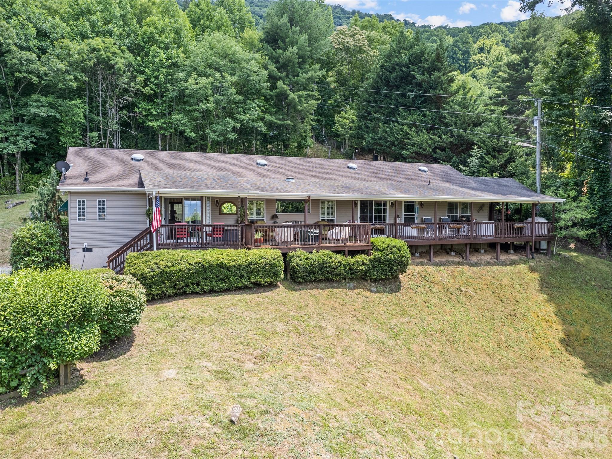 Private Ranch style home at high elevation with long range views, creek and pond. The home has been well maintained and the property landscaped with flowering trees and plants. Walk on to a huge wrap-around covered porch to enter the great room with loads of natural light and an outdoor dining area. Beautiful wood floors with a Gas fireplace centered in the great room. The great room opens to a Modern kitchen with Granite countertops, Oak cabinets and Stainless steel appliances. The split Bedroom plan has 2 ensuite Primary Bedrooms and a walkthrough closet and Duel bathrooms. At the opposite end of the home is the laundry room, large Den and an additional guest bedroom
The additional ensuite Bedroom has Duel Closets and a vaulted ceiling. The property has a small creek and pond with fish. Bring your friends for a entertaining in the outdoor dining area and grill. The home can be sold furnished.
Easy year round access and convenient to the the National Parks as well as Waynesville restaurants and shopping.